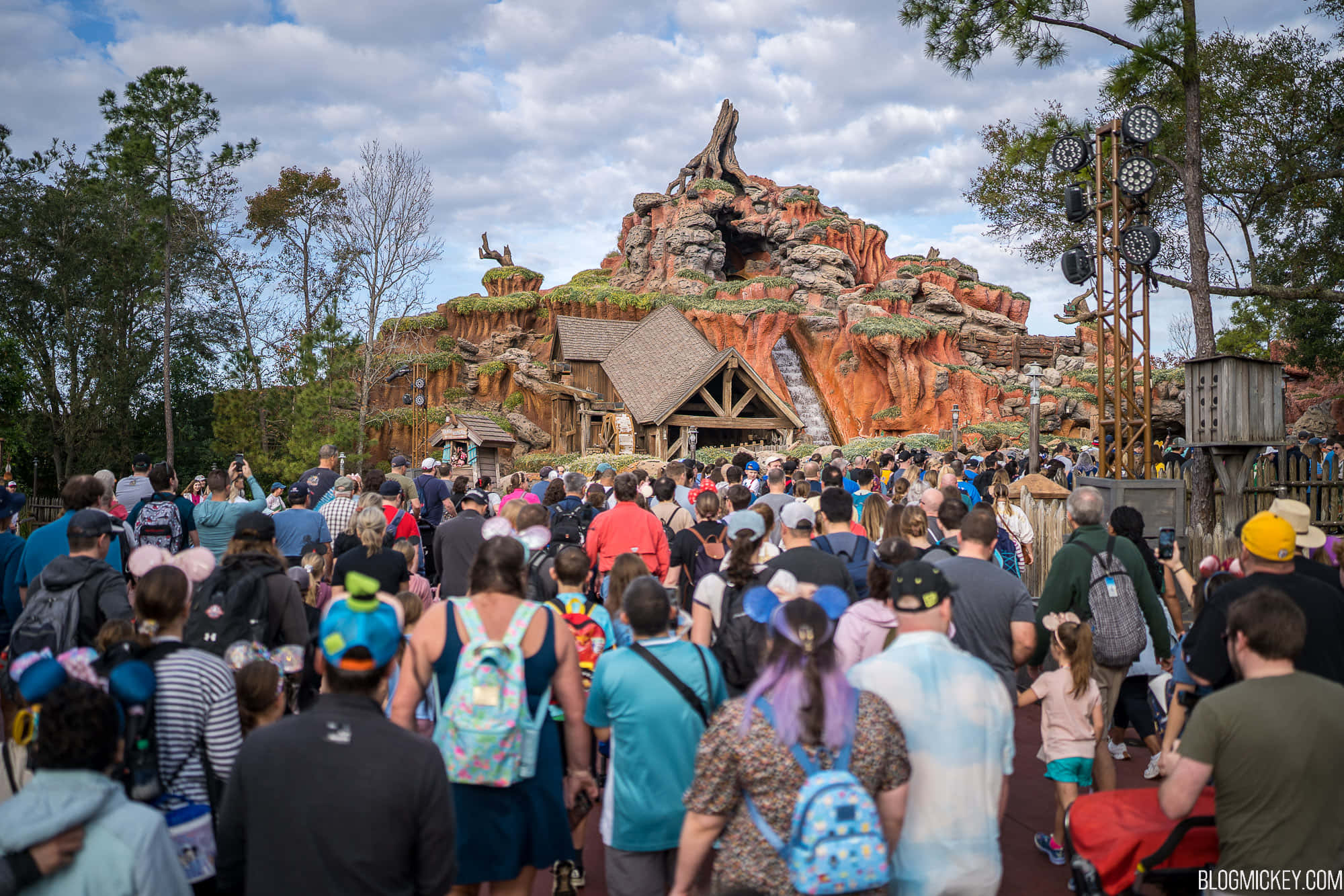 Splash Mountain 桌布 壁紙 — 一群遊客走向建在岩石懸崖邊的質樸木製景點，天空部分多雲。