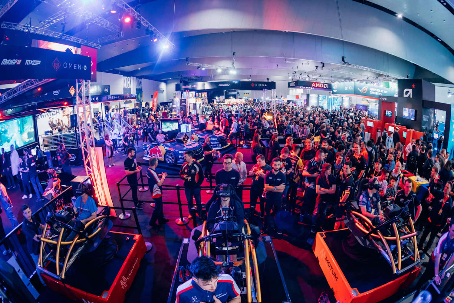 Gaming Conventions 桌布 壁紙 — 一群遊戲玩家在閃爍的霓虹燈下，沉浸於充滿活力的電競大會中的賽車模擬器。