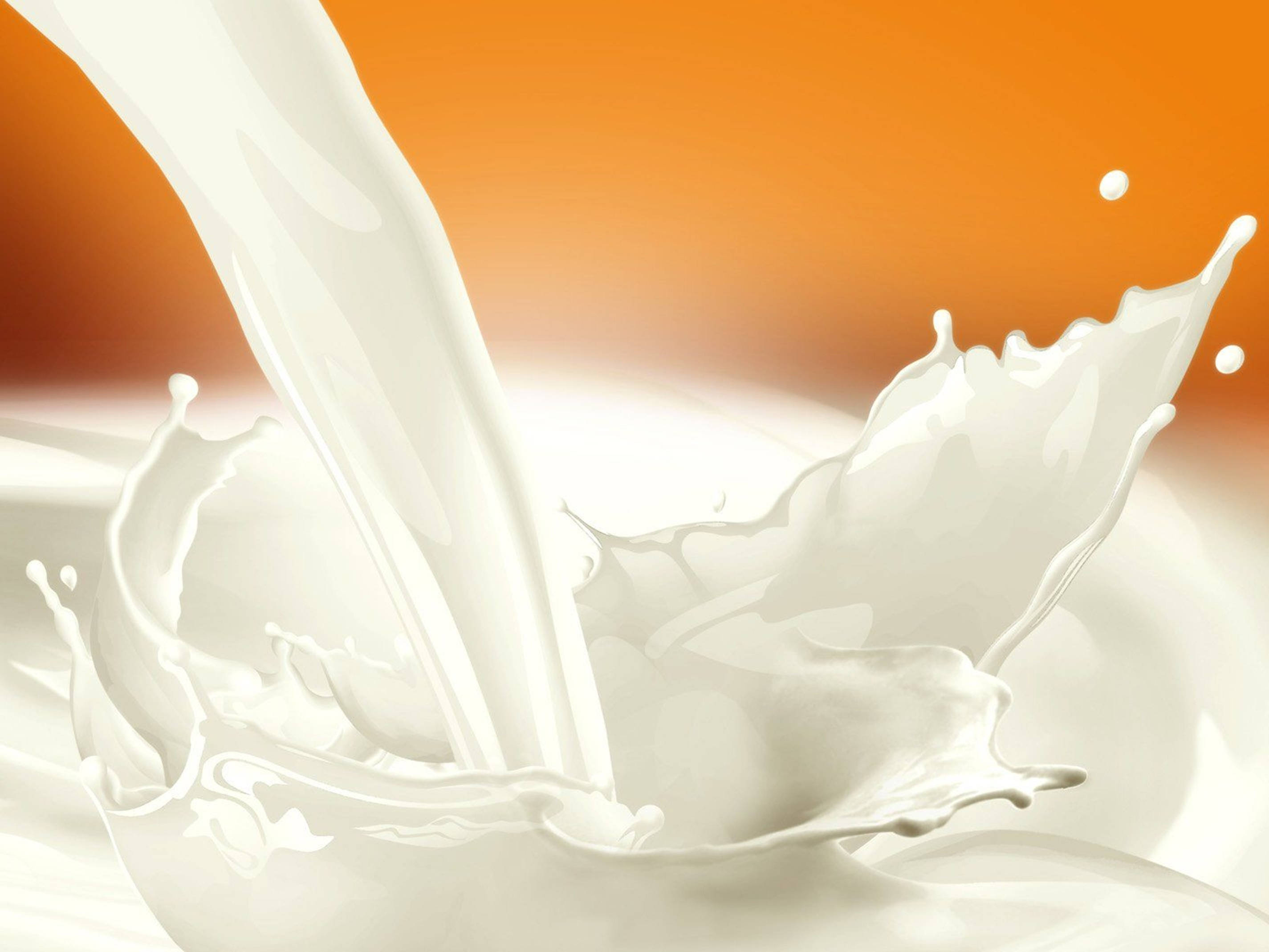 Drink 桌布 壁紙 — 一股乳白色液體在溫暖的橙色漸層背景上動態飛濺。