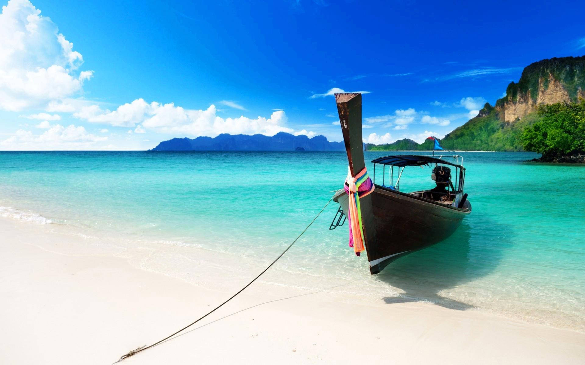 Caribbean 桌布 壁紙 — 一艘傳統長尾船停泊在 pristine 白色沙灘上，四周是碧綠的海水和鬱鬱蔥蔥的綠色懸崖，天空湛藍。