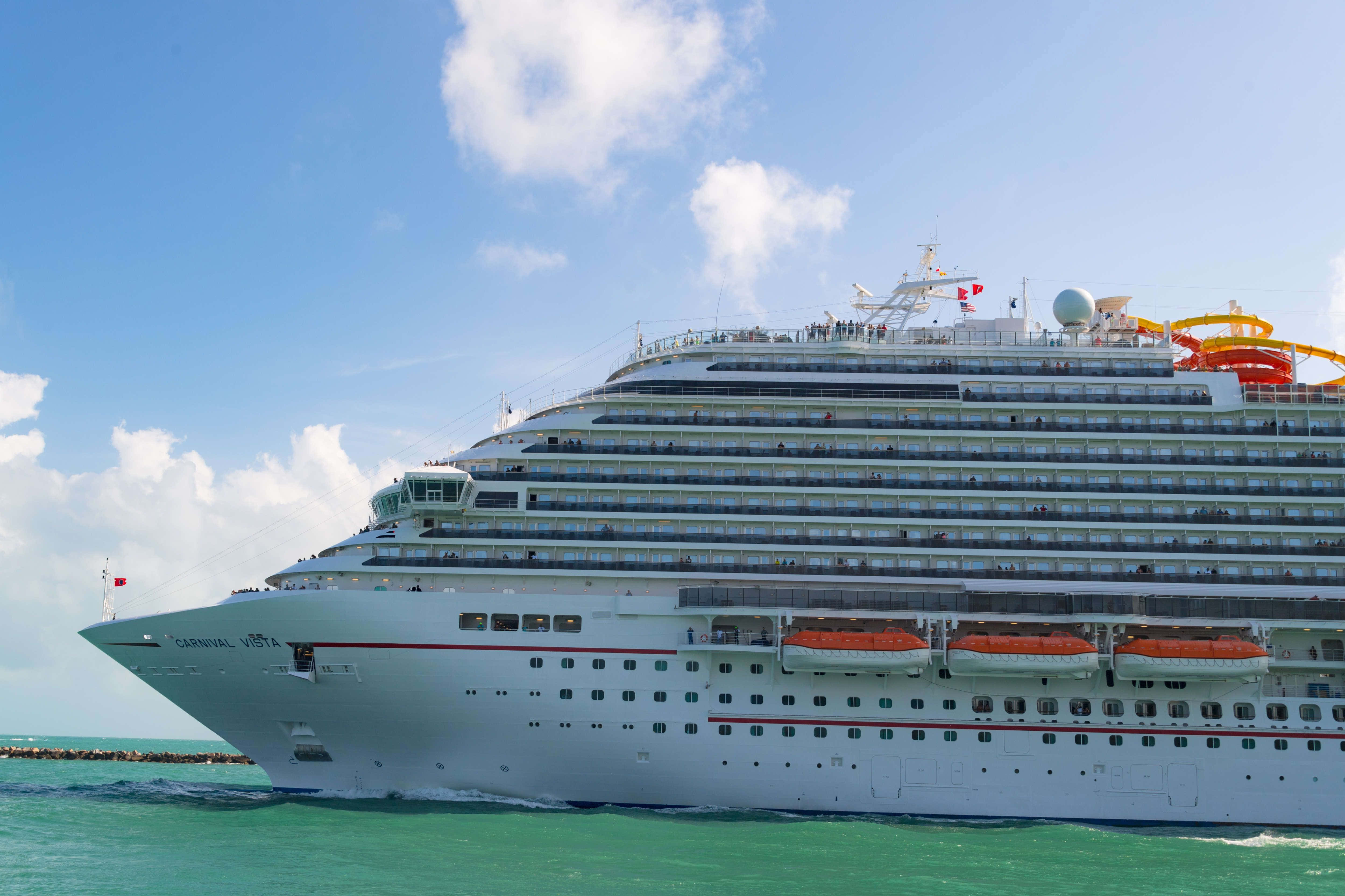 Carnival Dream 桌布 壁紙 — 一艘名為 Carnival Vista 的巨型白色郵輪在蔚藍的天空和蓬鬆雲朵下，航行於碧綠色的水域中。