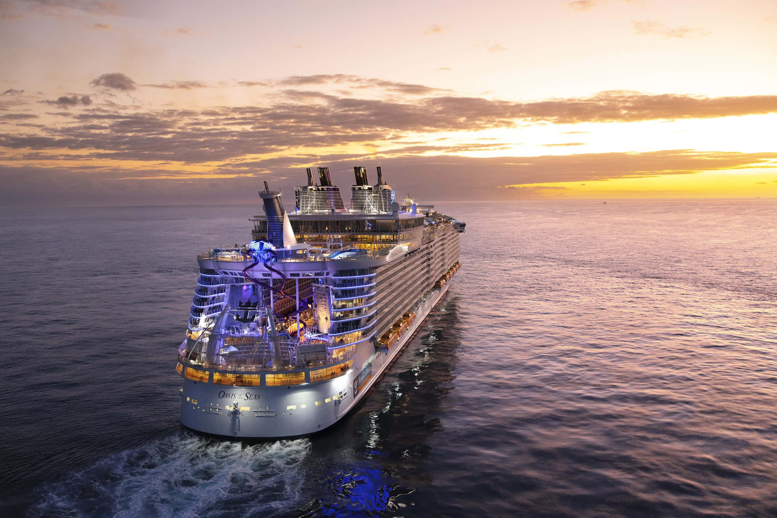 郵輪 桌布 壁紙 — 一艘名為 Oceania Sails 的巨型郵輪在日落時分滑過平靜的海面，溫暖的金色和紫色色調倒映在水中。