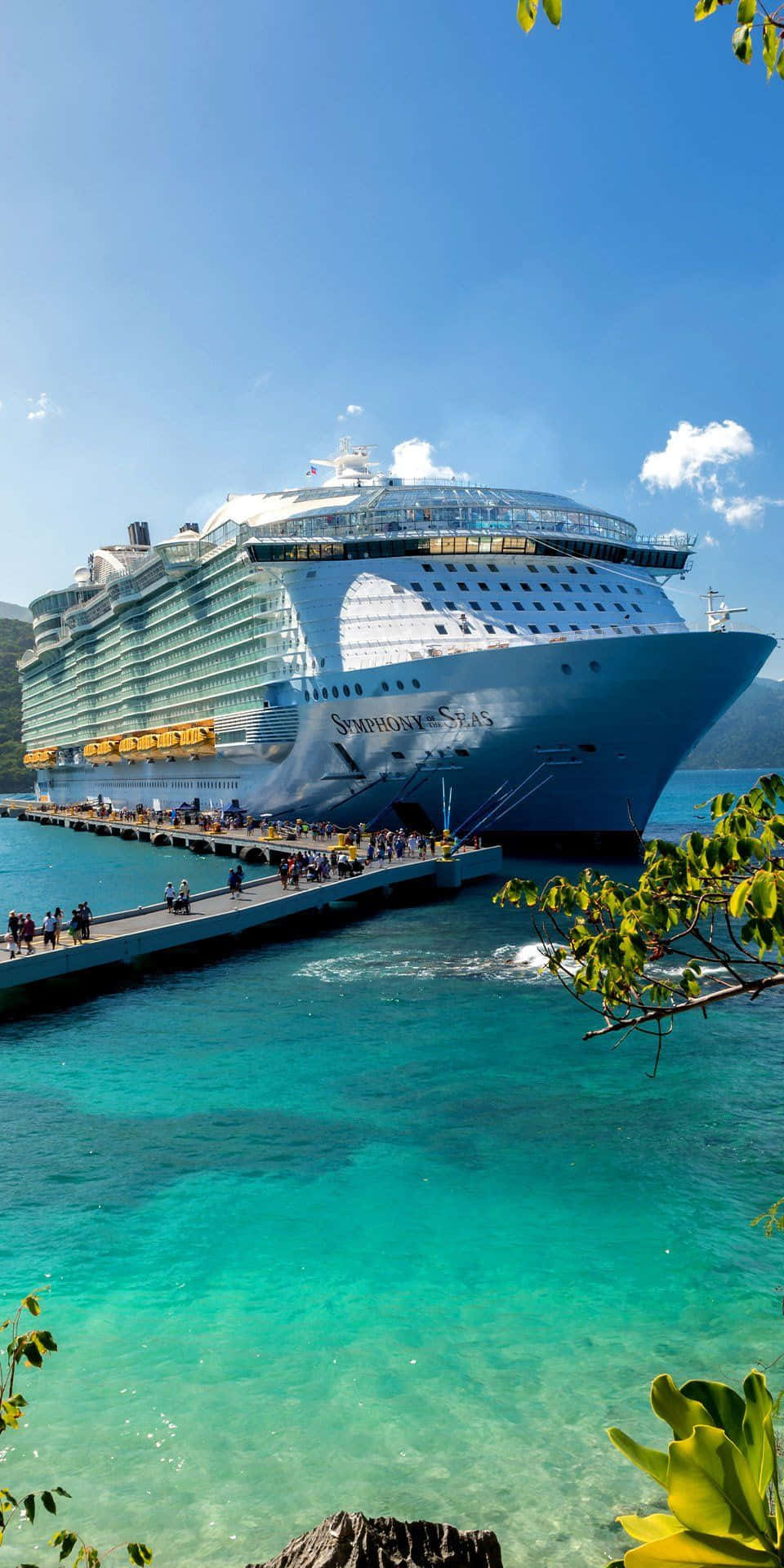 Cruise 桌布 壁紙 — 一艘名為Symphony of the Seas的巨型郵輪停泊在熱帶碼頭，天空清澈湛藍，海水呈碧綠色。