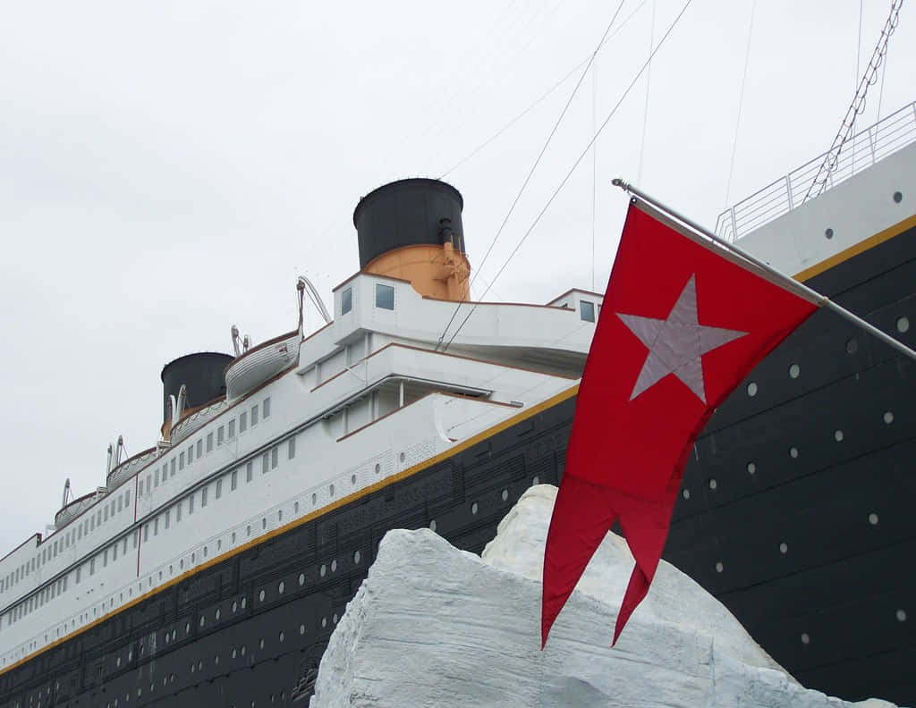 Titanic 桌布 壁紙 — 一艘大型復古遠洋郵輪聳立在積雪的冰山之上，前景中一面帶有白色星星的紅旗隨風飄揚。