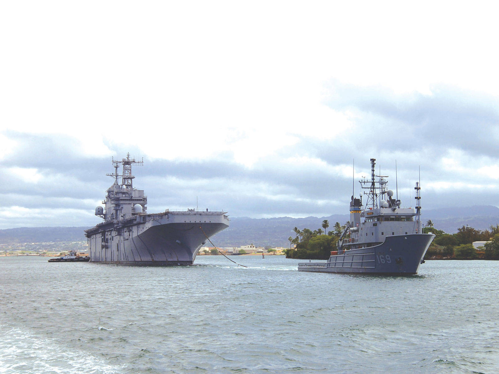 航空母艦和軍艦在陰天下的港口航行。