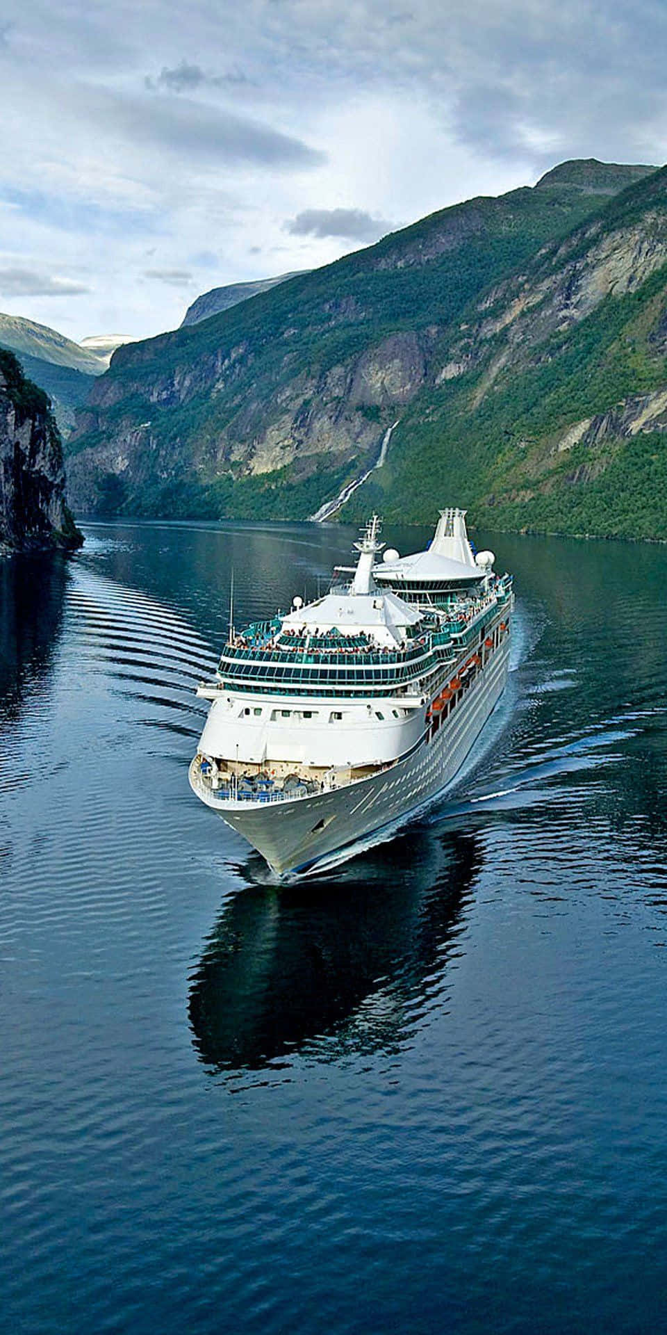 Cruise 桌布 壁紙 — 一艘大型郵輪在陰天之下，航行於深藍色峽灣，兩旁是高聳的綠色山脈。