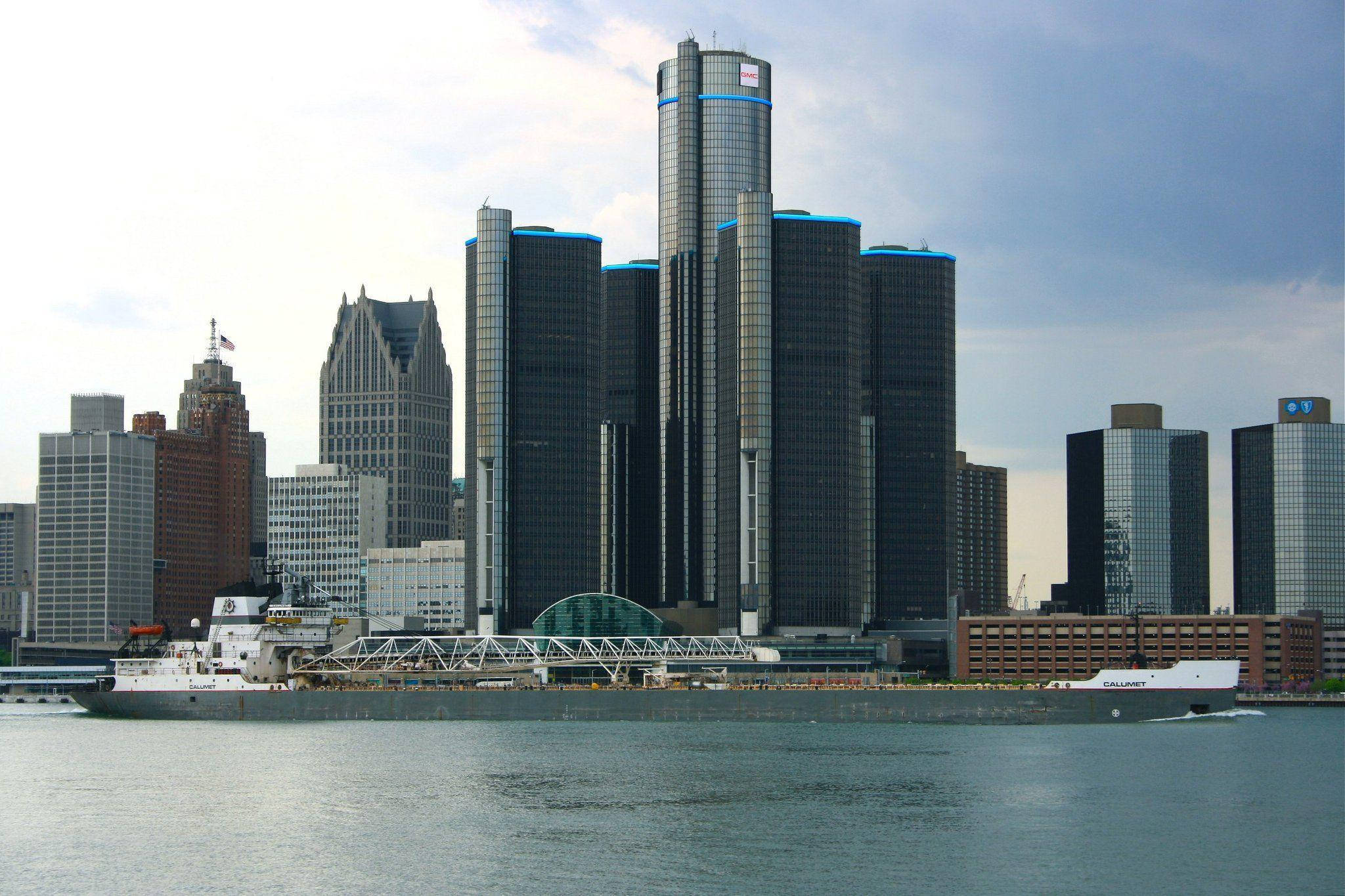 detroit 桌布 壁紙 — 一艘大船在部分多雲的天空下駛過標誌性的文藝復興中心摩天大樓。