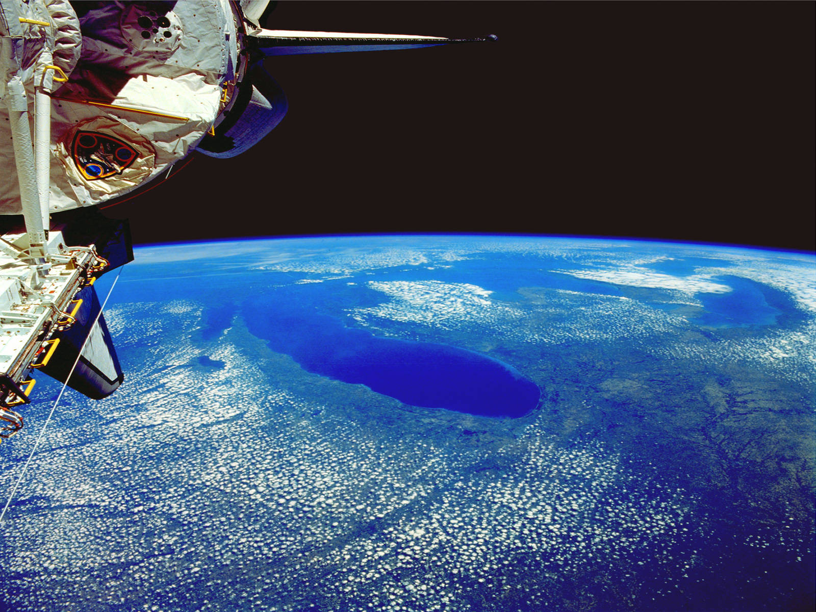 nasa 美學 桌布 壁紙 — 一艘太空船從太空的黑色虛空中俯瞰地球充滿活力的藍色海洋和旋轉的白雲。