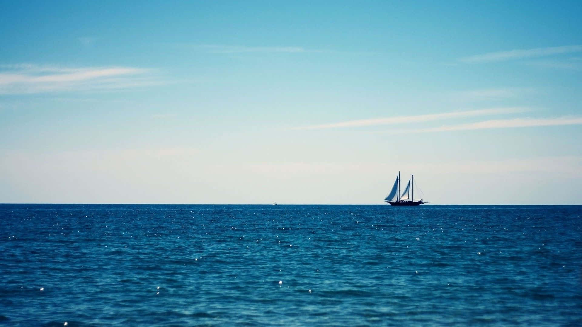 Minimalist Ocean 桌布 壁紙 — 一艘孤獨的帆船在晴朗的天空下，伴隨著縷縷輕雲，滑過廣闊的藍色海洋。