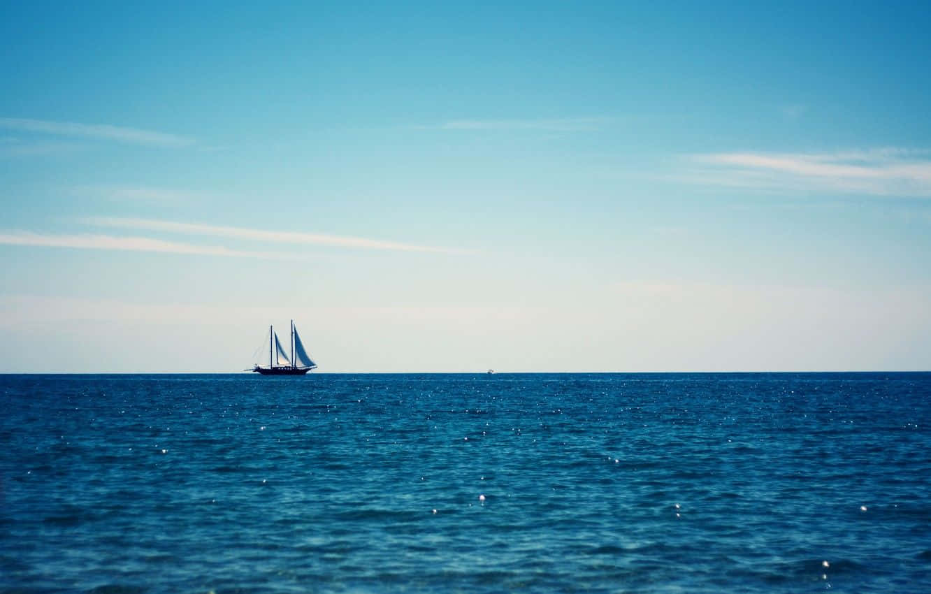Sailboat 桌布 壁紙 — 一艘孤獨的帆船在晴朗的天空下，伴隨著縷縷白雲，滑過廣闊的藍色海洋。