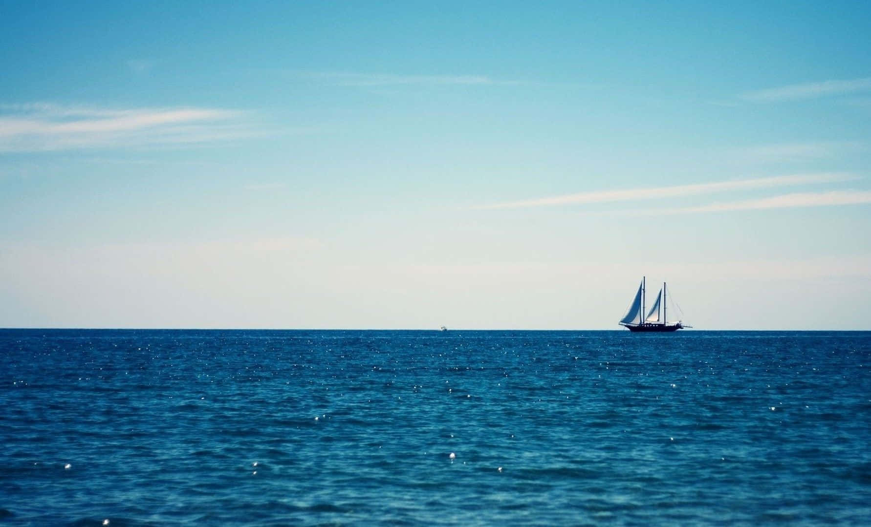 Sailboat 桌布 壁紙 — 一艘孤獨的帆船在晴朗的天空和縷縷白雲下，滑過廣闊的藍色海洋。