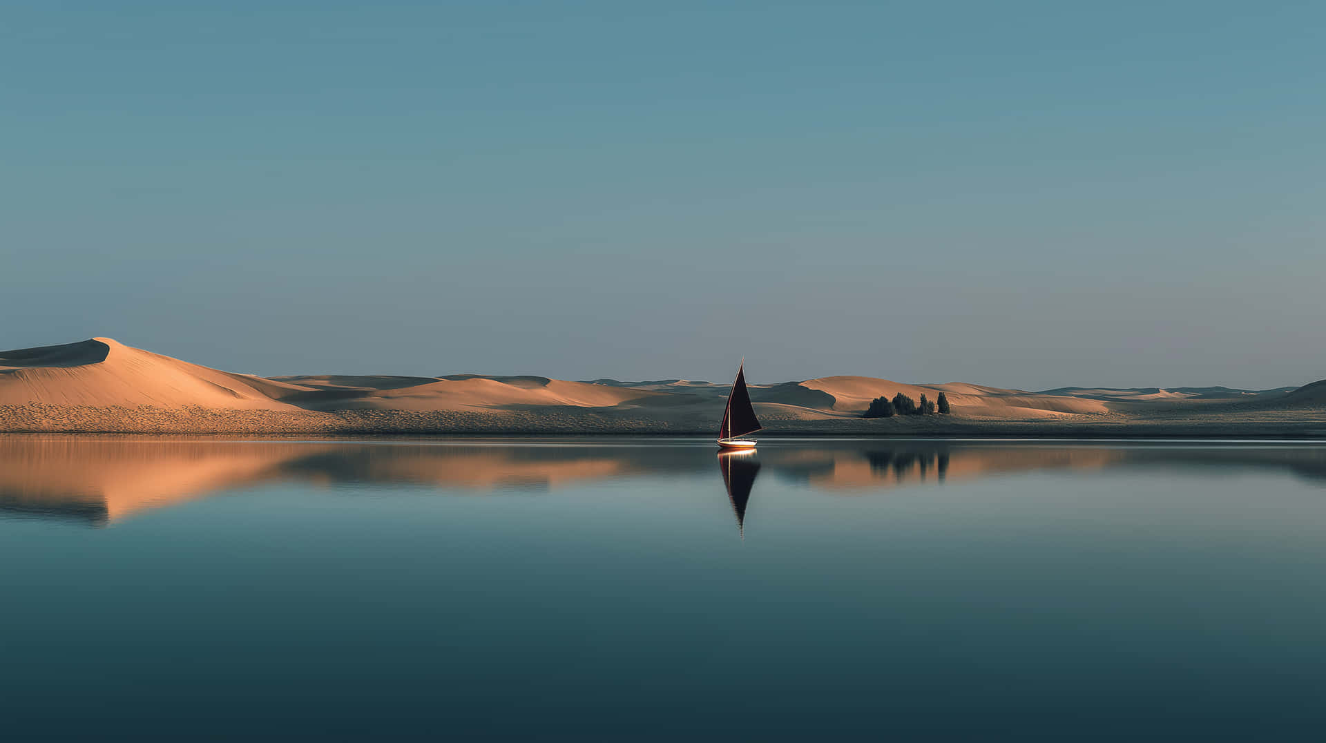 Sailboat on vast, calm water with distant desert landscape 壁紙 — 一艘孤獨的帆船在玻璃般的湖面上滑行，映照著金色沙丘，天空寧靜湛藍。