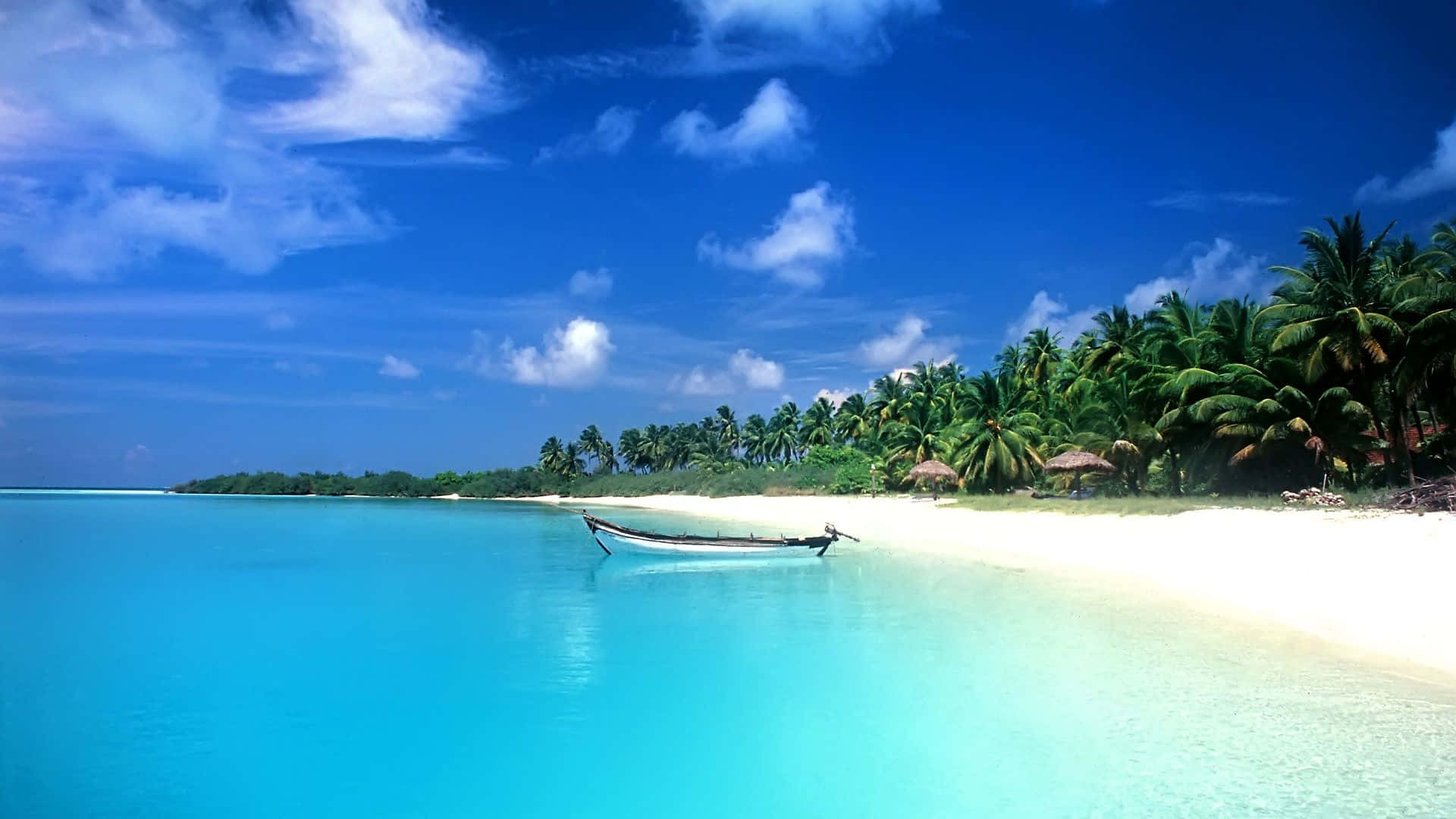 Hi Res Beach 桌布 壁紙 — 一艘孤獨的木船停泊在 pristine 白色沙灘上，旁邊是碧綠的海水，上方是藍天白雲。