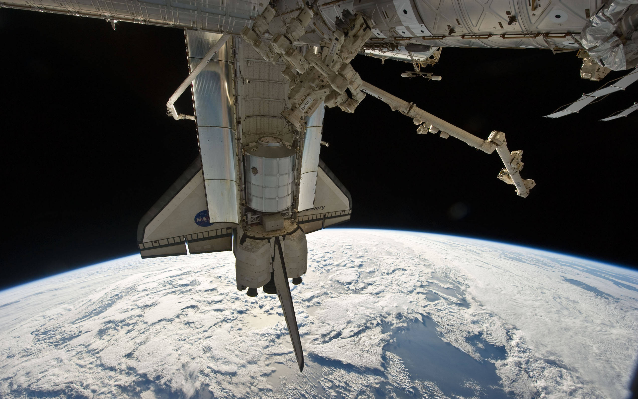 nasa 美學 桌布 壁紙 — 一艘對接在國際太空站的太空梭，懸浮在地球彎曲的地平線之上，下方有旋轉的雲層。