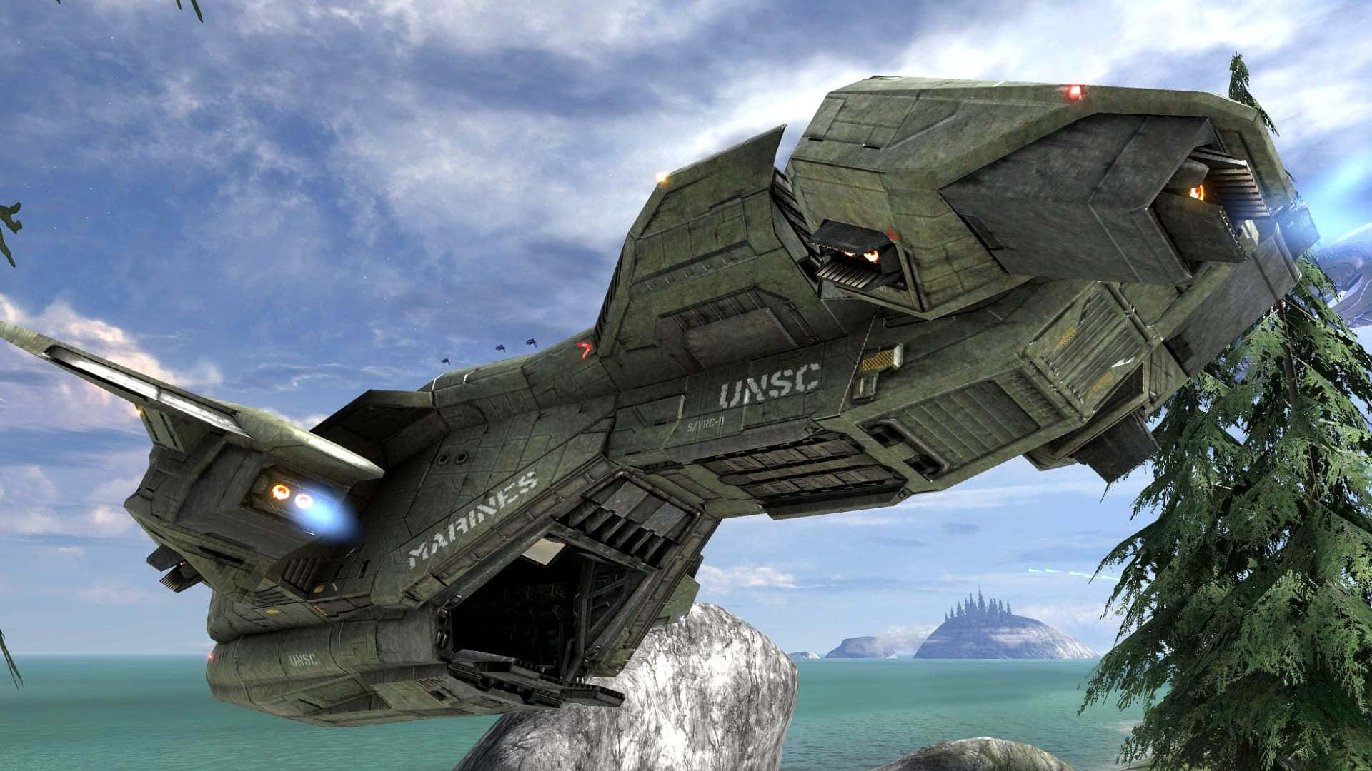 Scorpion Halo 桌布 壁紙 — 一艘巨大的UNSC海軍陸戰隊運輸艦在岩石海岸線上盤旋，周圍有松樹和遠處的島嶼，天空部分多雲。