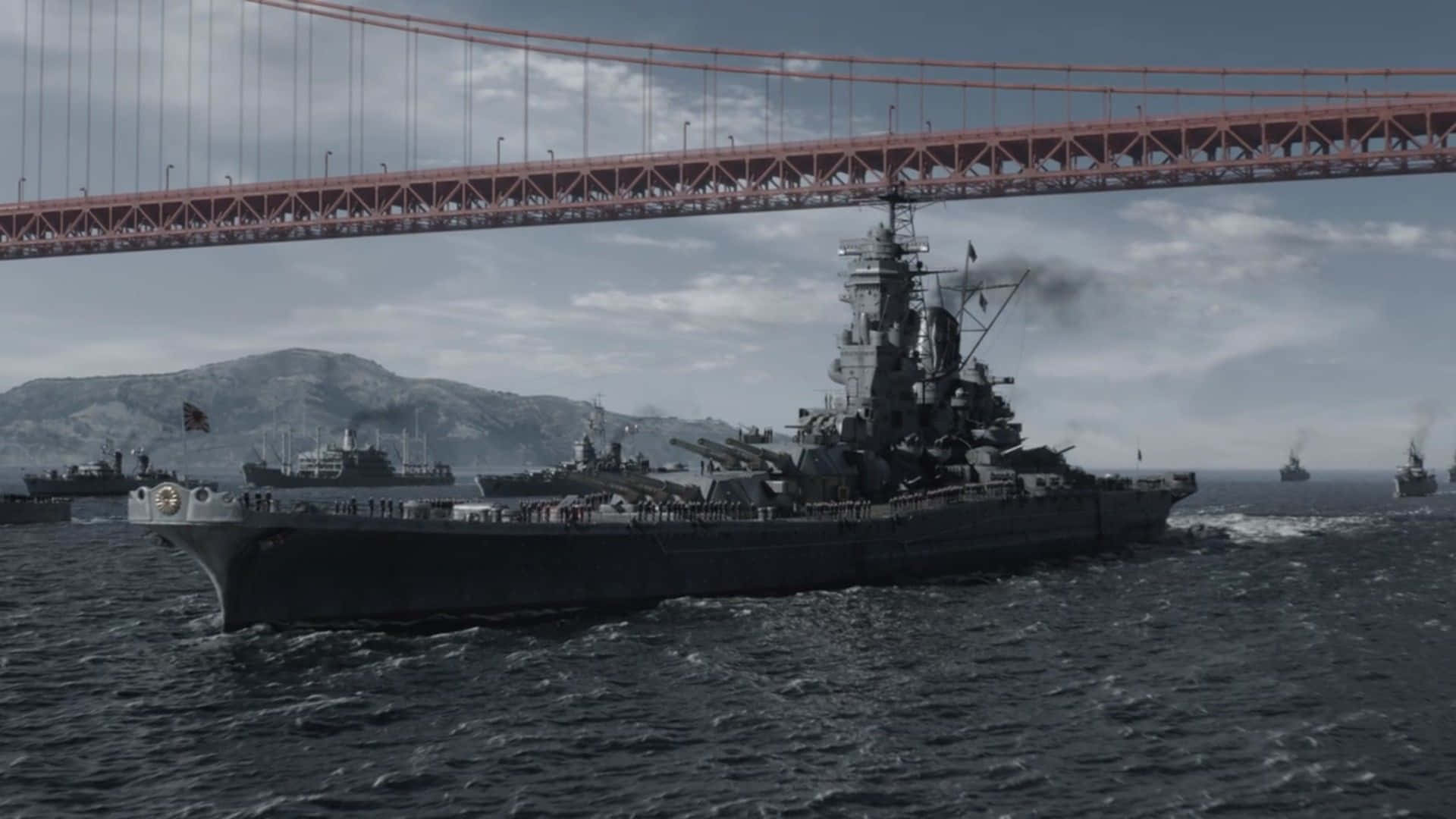  壁紙 — 一艘巨大的戰艦在陰天之下，於舊金山灣中其他軍艦的伴隨下，航行於標誌性的金門大橋下方。