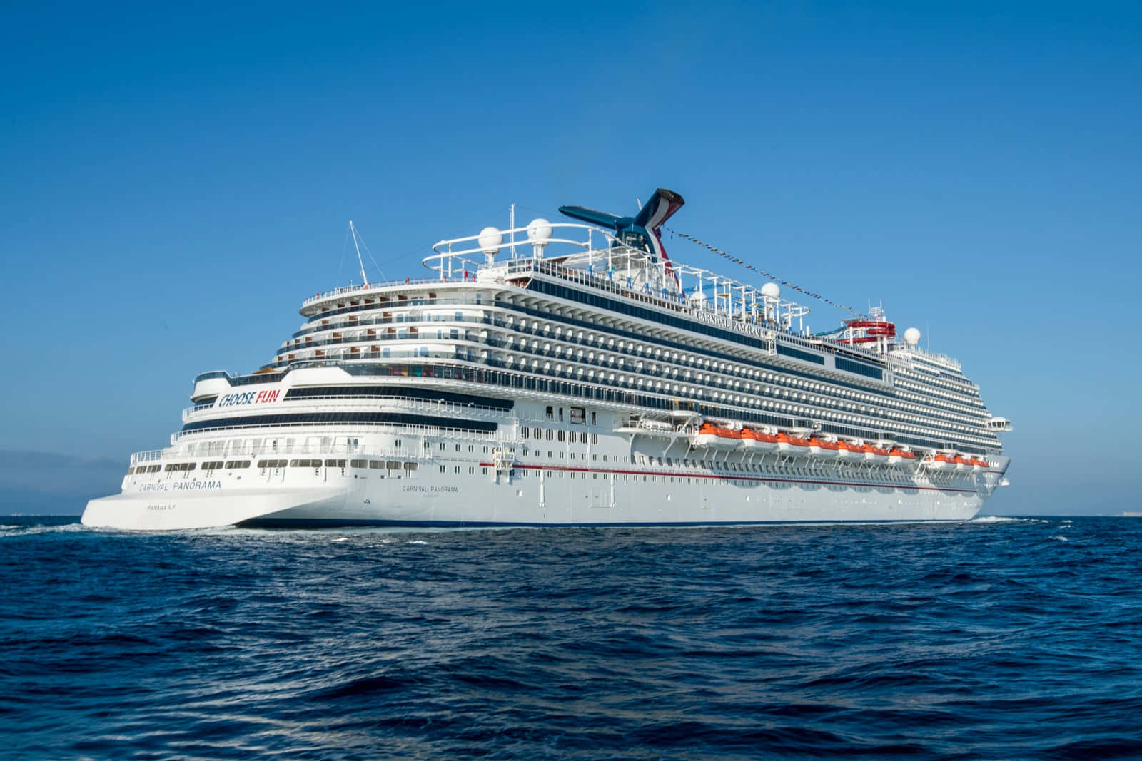 Carnival Dream 桌布 壁紙 — 一艘巨大的白色嘉年華全景號郵輪在清澈的藍天下優雅地航行在深藍色的海洋中。