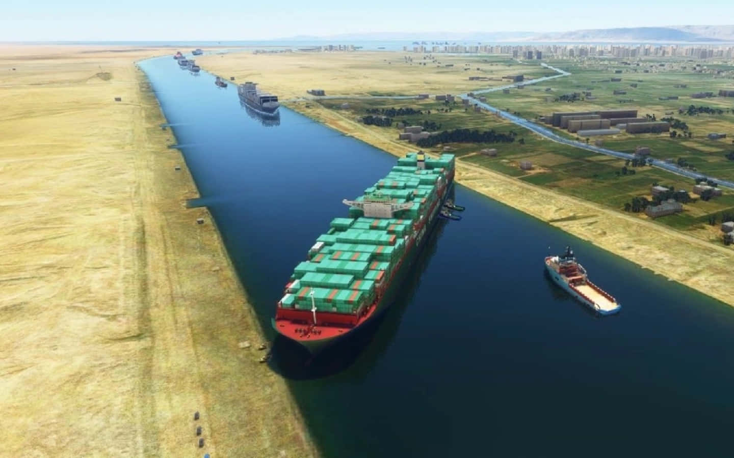 Cargo Ship 桌布 壁紙 — 一艘巨大的貨櫃船在晴朗的天空下，航行在一條狹窄的運河中，兩旁是乾旱的沙漠和遠處的城市擴張。