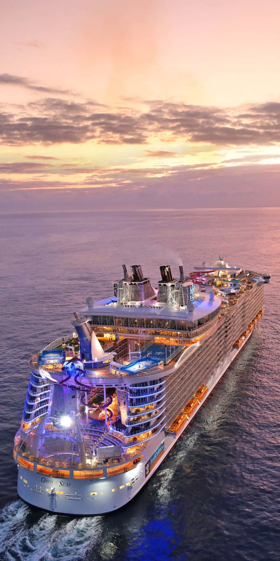 Cruise 桌布 壁紙 — 一艘巨大的郵輪在日落時分航行於平靜的海面上，閃爍的燈光照亮了甲板和泳池。