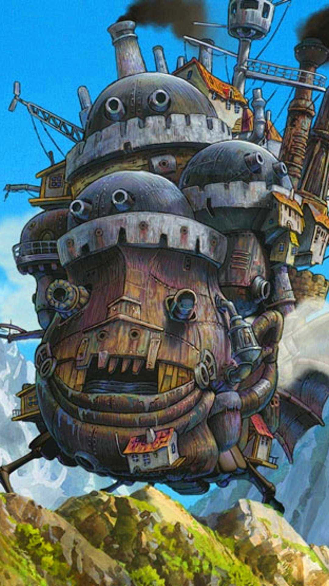 Studio Ghibli Phone 桌布 壁紙 — 一艘巨大的飛行飛船，帶有異想天開的臉和工業管道，在明亮的藍天下盤旋在山區景觀之上。