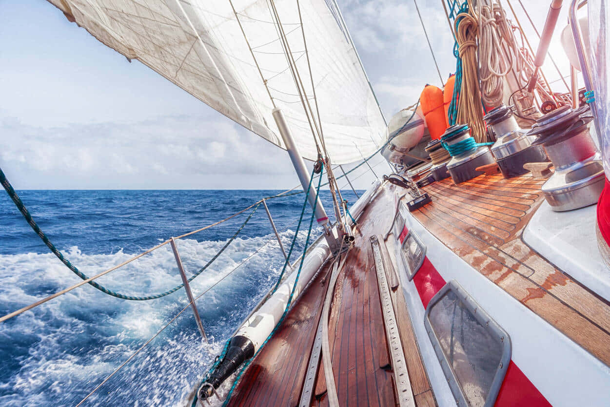 Sailboat 桌布 壁紙 — 一艘帶有白色帆的帆船在明亮的天空下劃過深藍色的海浪。