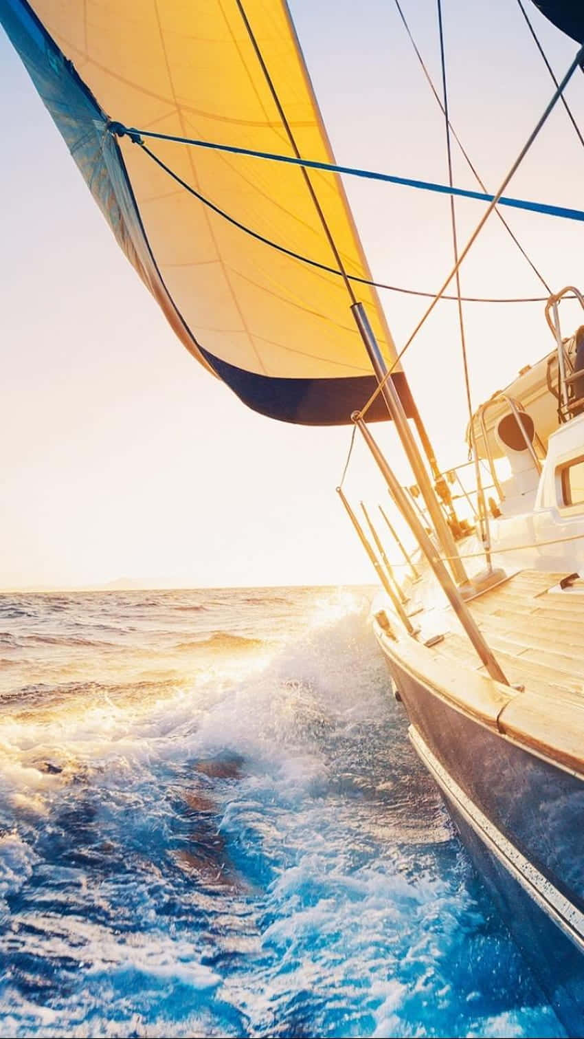 Sailboat 桌布 壁紙 — 一艘帶有鮮黃色帆的帆船在金色日落中劃過閃閃發光的藍色海浪。