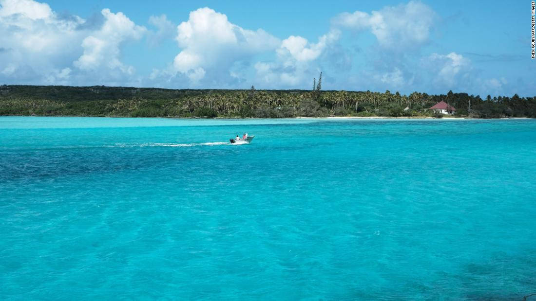島嶼 桌布 壁紙 — 一艘快艇劃過充滿活力的碧綠海水，駛向一個鬱鬱蔥蔥的綠色島嶼，天空湛藍，白雲朵朵。