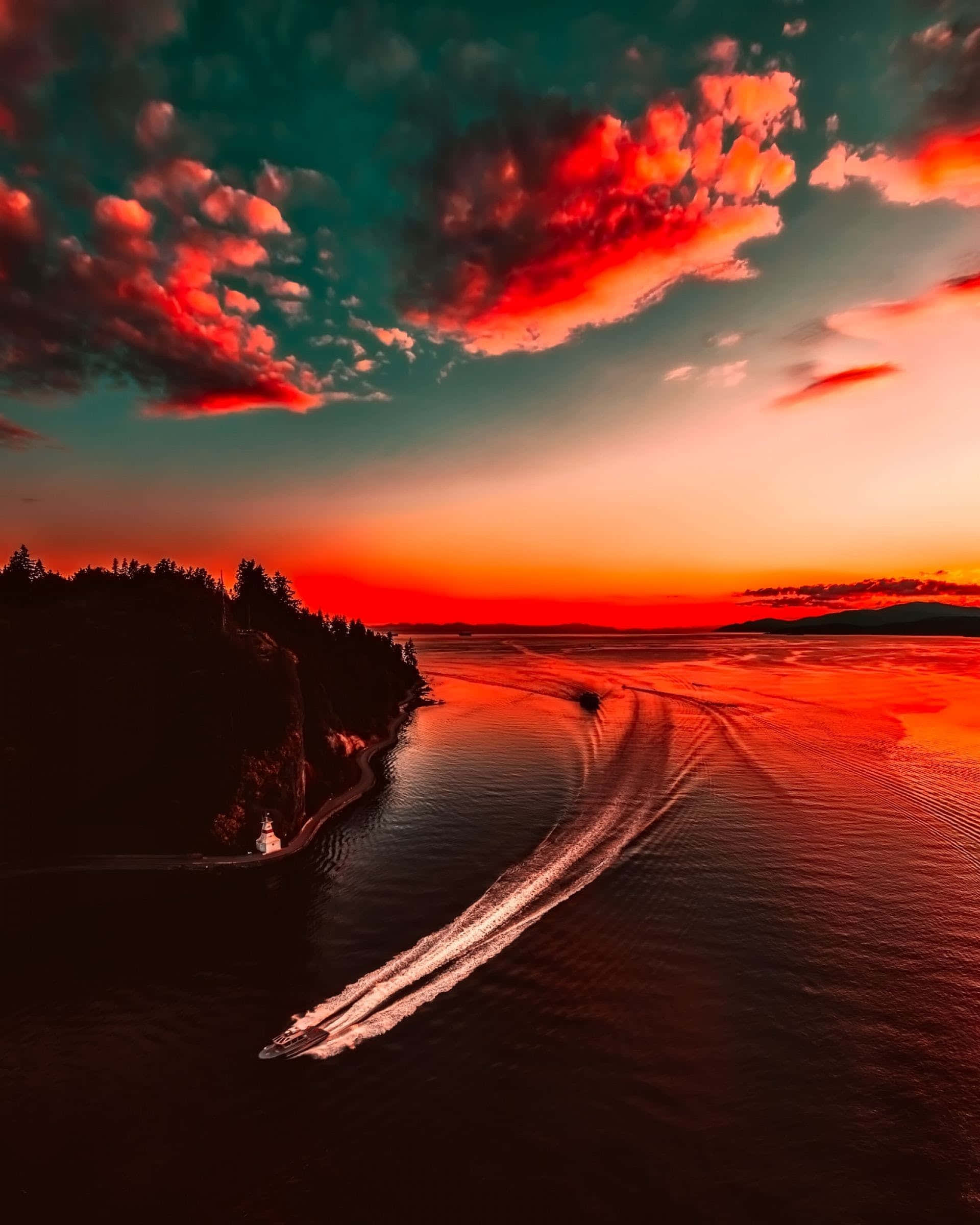 Red Sunset 桌布 壁紙 — 一艘快艇在火紅的夕陽天空和戲劇性的雲彩下，劃過發光的紅色水面。