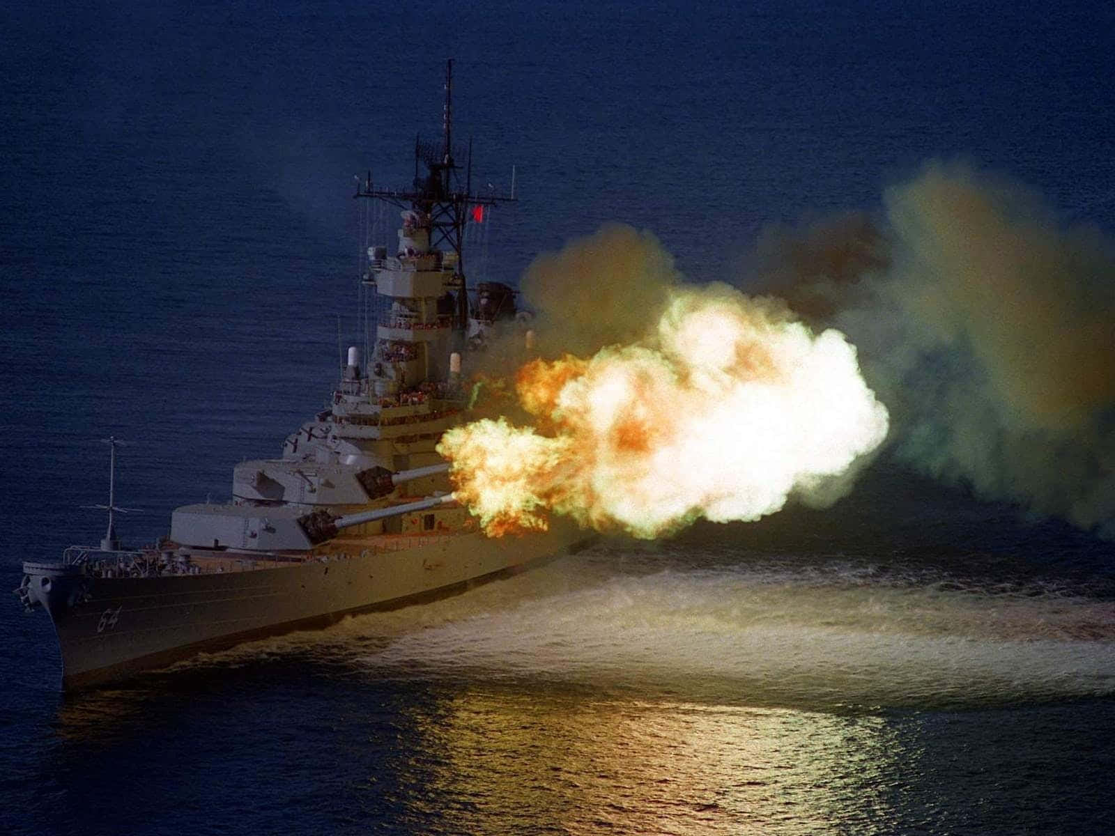 Battleships 桌布 壁紙 — 一艘戰艦在夜間發射巨型大砲，將明亮的橙色和白色爆炸送入黑暗的海洋。