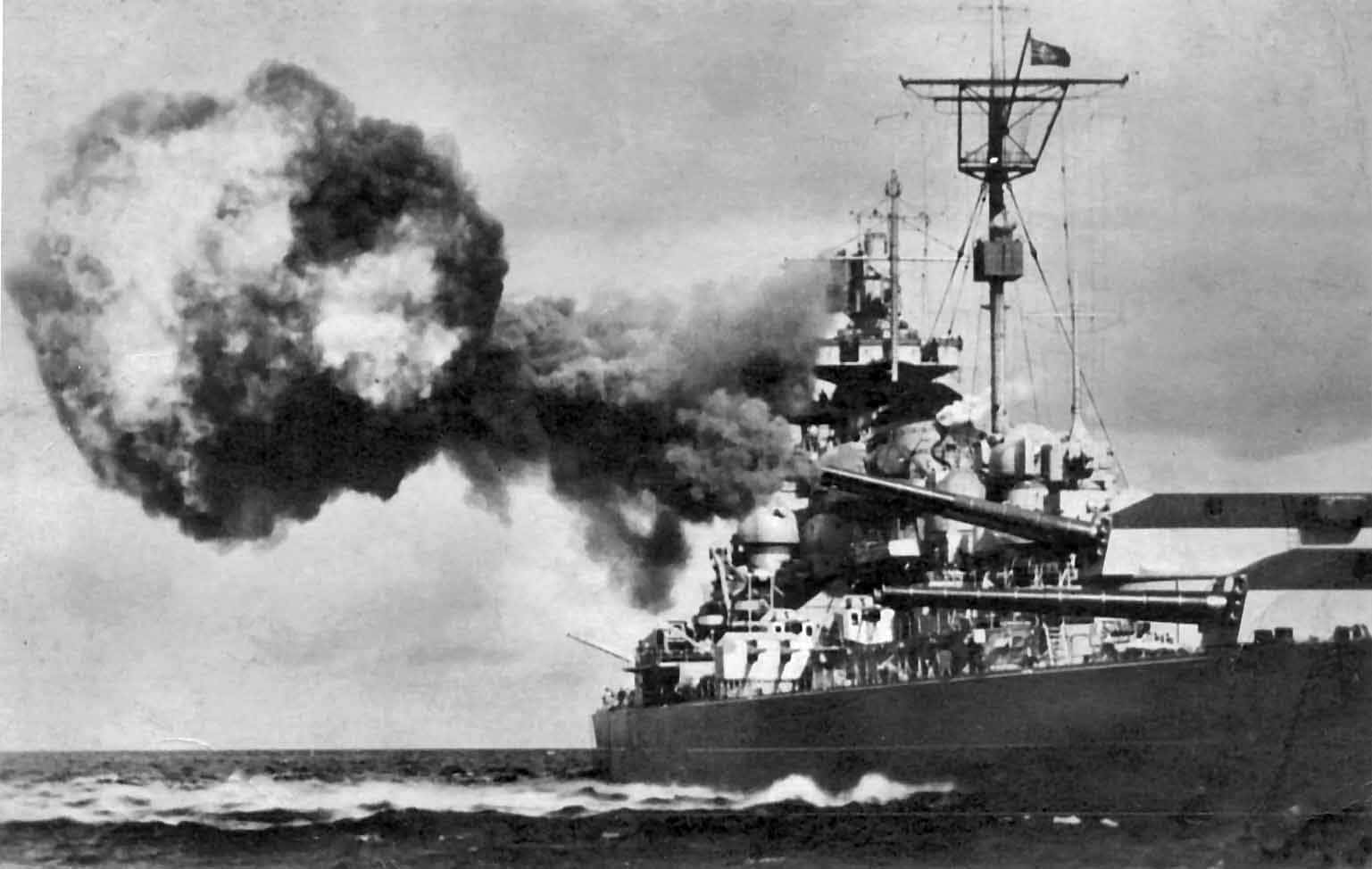 Battleships 桌布 壁紙 — 一艘戰艦發射主砲，在波濤洶湧的海面上切開，向陰沉的天空噴出巨大的煙霧。
