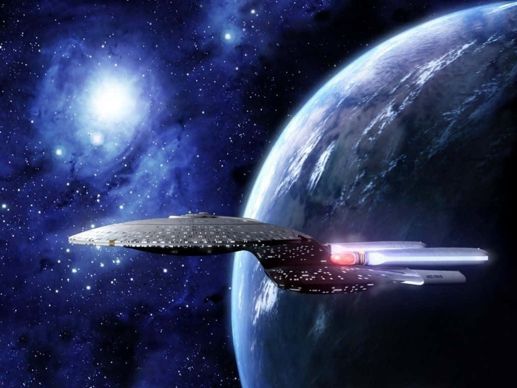 Star Trek Enterprise 桌布 壁紙 — 一艘星艦在佈滿星星的星雲背景下，掠過一顆藍色行星，旁邊有明亮的太陽。