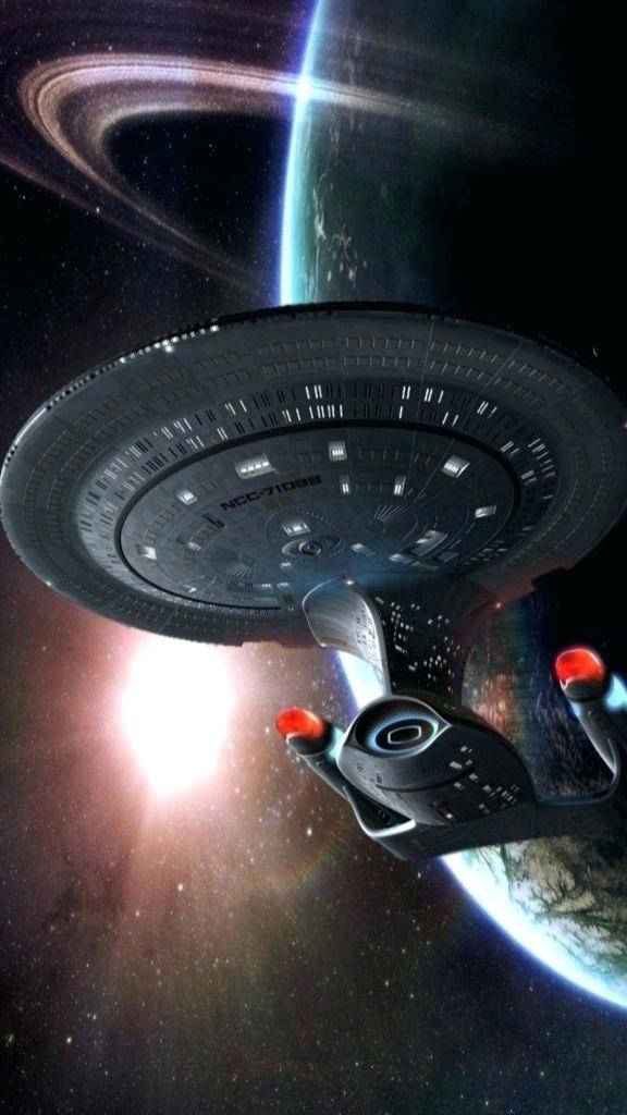 darkness 桌布 壁紙 — 一艘星際聯邦星艦在深空中滑過一顆帶環行星，背後有發光的星爆。