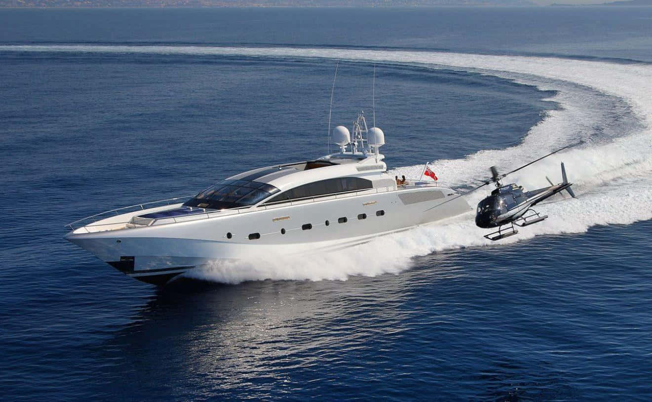 Yacht 桌布 壁紙 — 一艘時尚的白色豪華遊艇在深藍色的海洋上高速行駛，附近有一架直升機掠過水面。