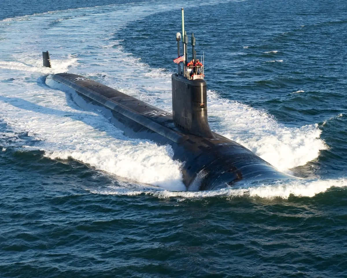 Submarine 桌布 壁紙 — 一艘時尚的黑色潛艇劃破深藍色的海浪，在明亮的日光下留下泡沫般的白色尾跡。