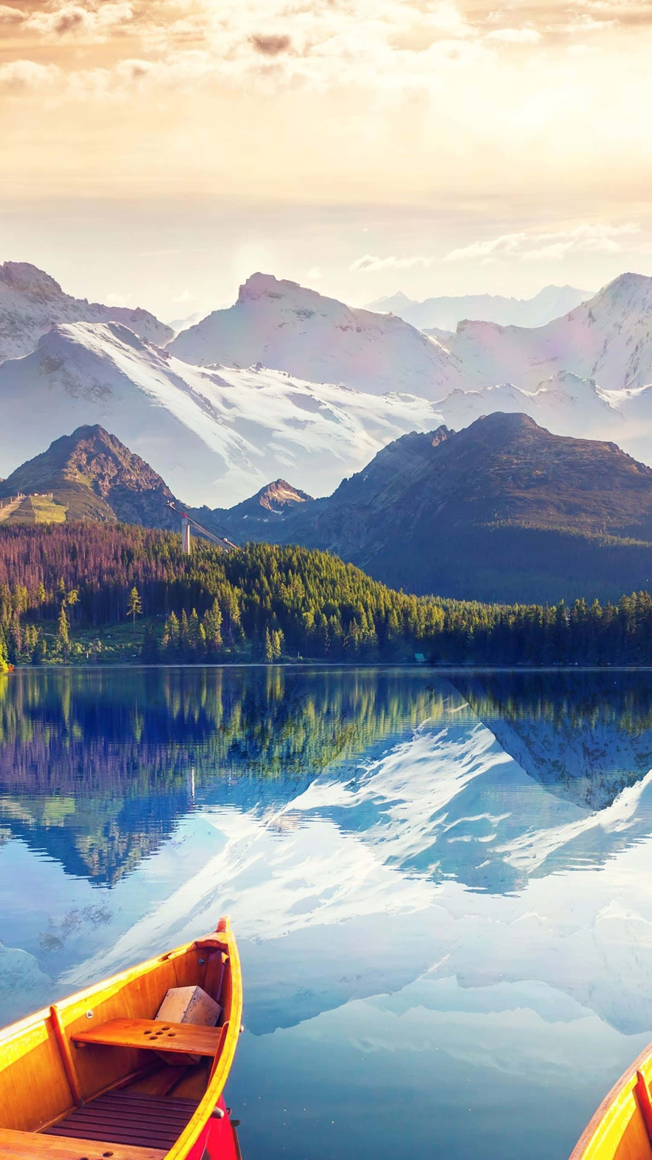 Nature Scenes 桌布 壁紙 — 一艘木製獨木舟停泊在如鏡般的阿爾卑斯山湖邊，倒映著白雪覆蓋的山峰，天空呈現金色日出。