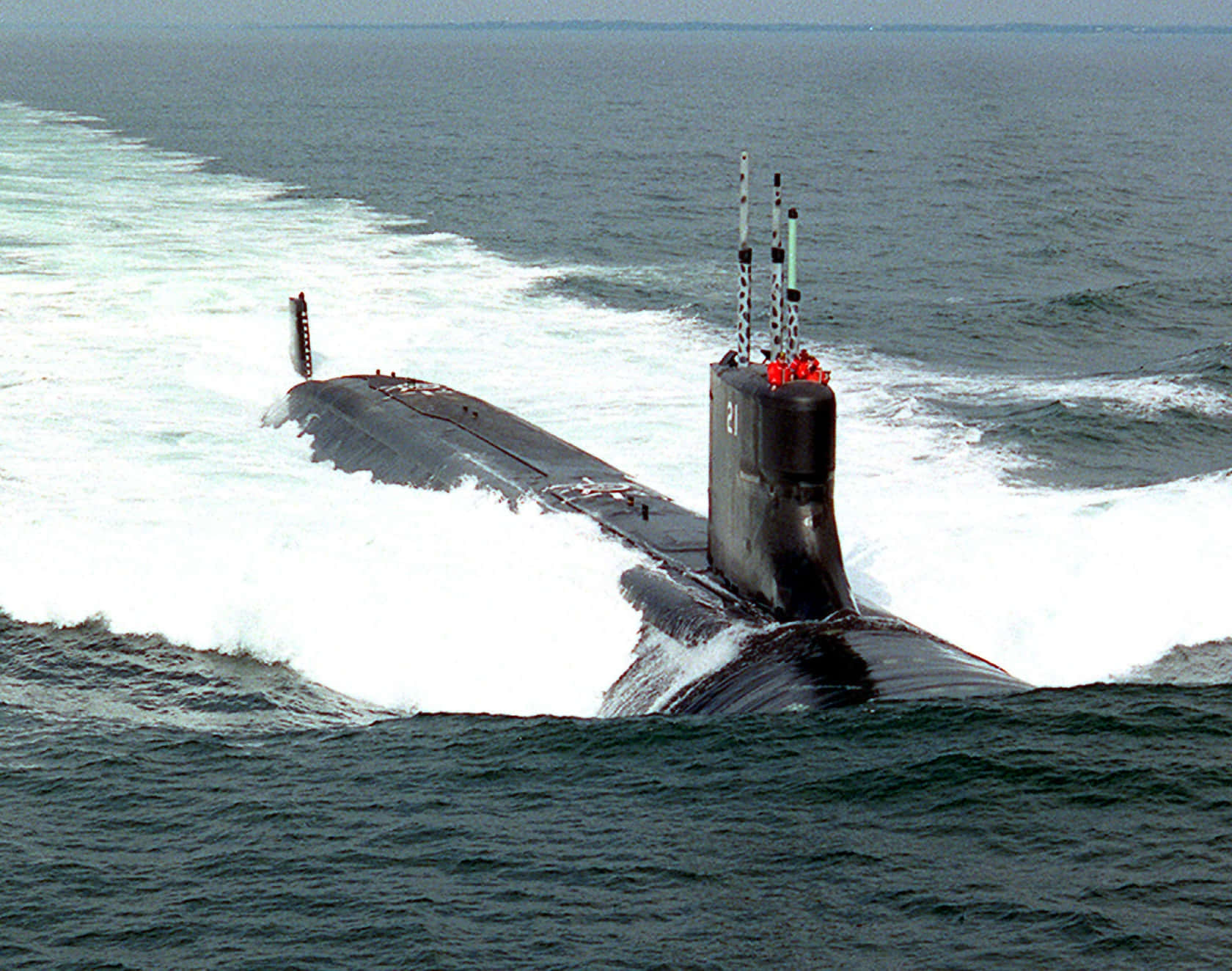 Submarine 桌布 壁紙 — 一艘流線型黑色潛艇穿過波濤洶湧的海浪浮出水面，留下白色泡沫尾跡。