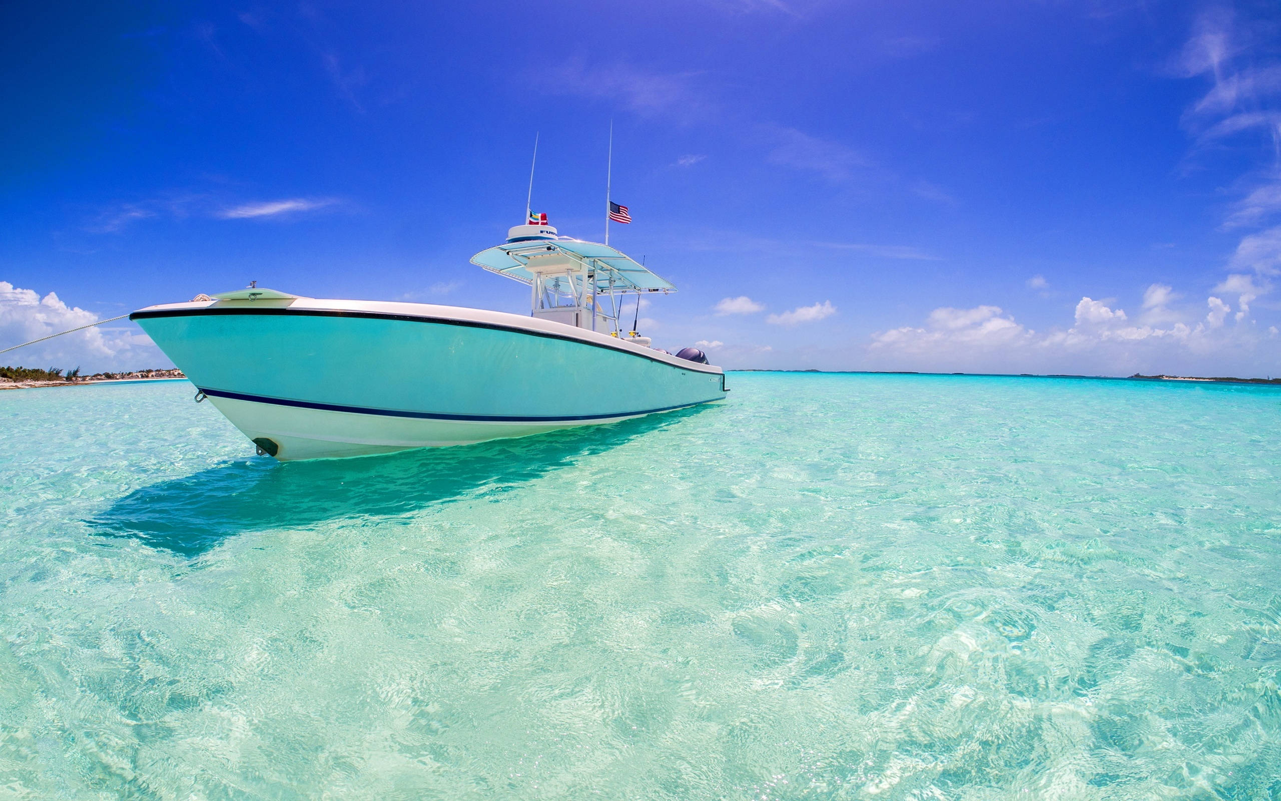 Nassau Bahamas 桌布 壁紙 — 一艘淺藍色漁船在清澈碧綠的海水上寧靜漂浮，天空湛藍，白雲點綴。