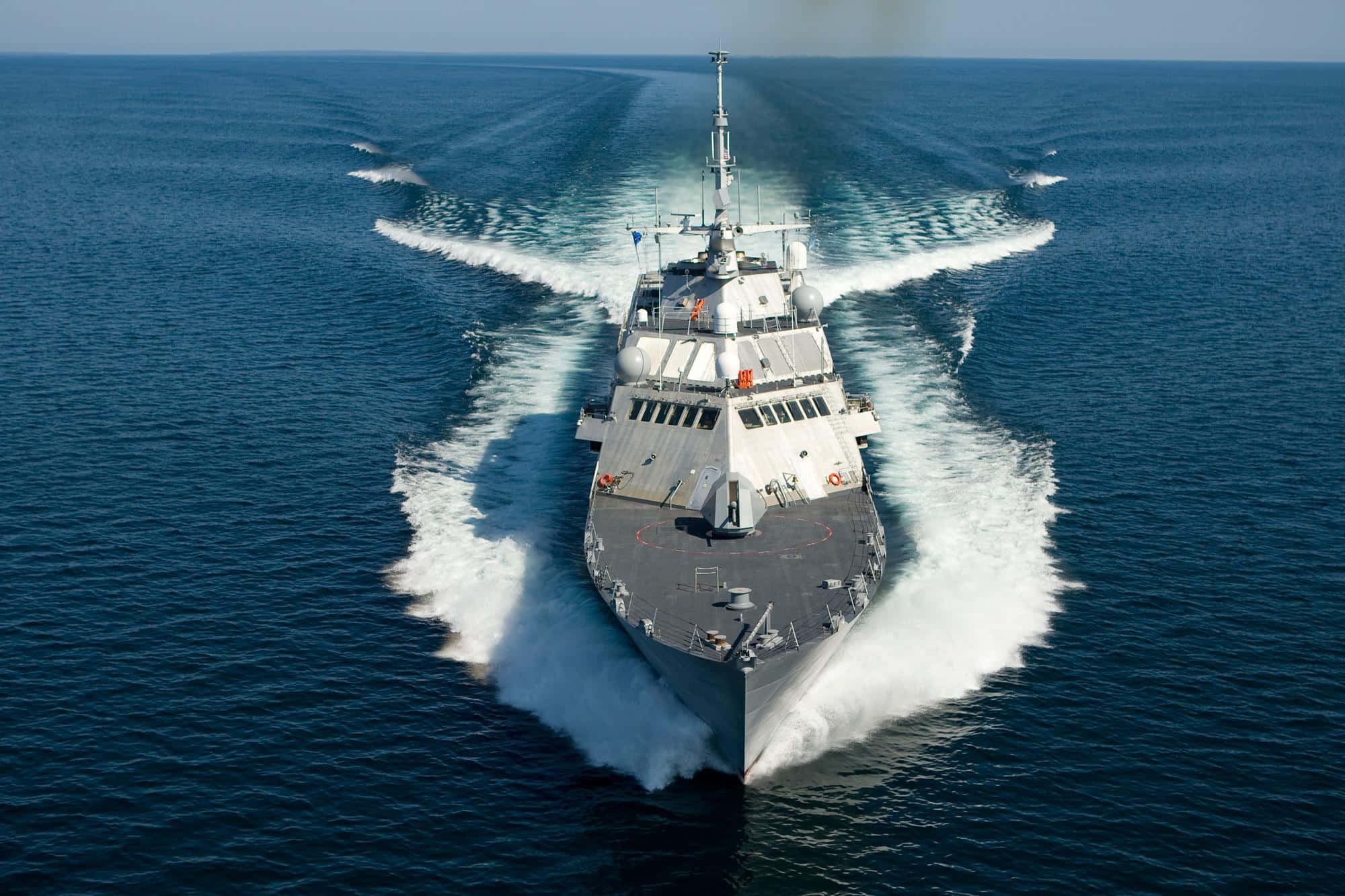 Navy 桌布 壁紙 — 一艘現代軍艦劃破深藍色海水，在晴朗天空下留下強大的白色航跡。