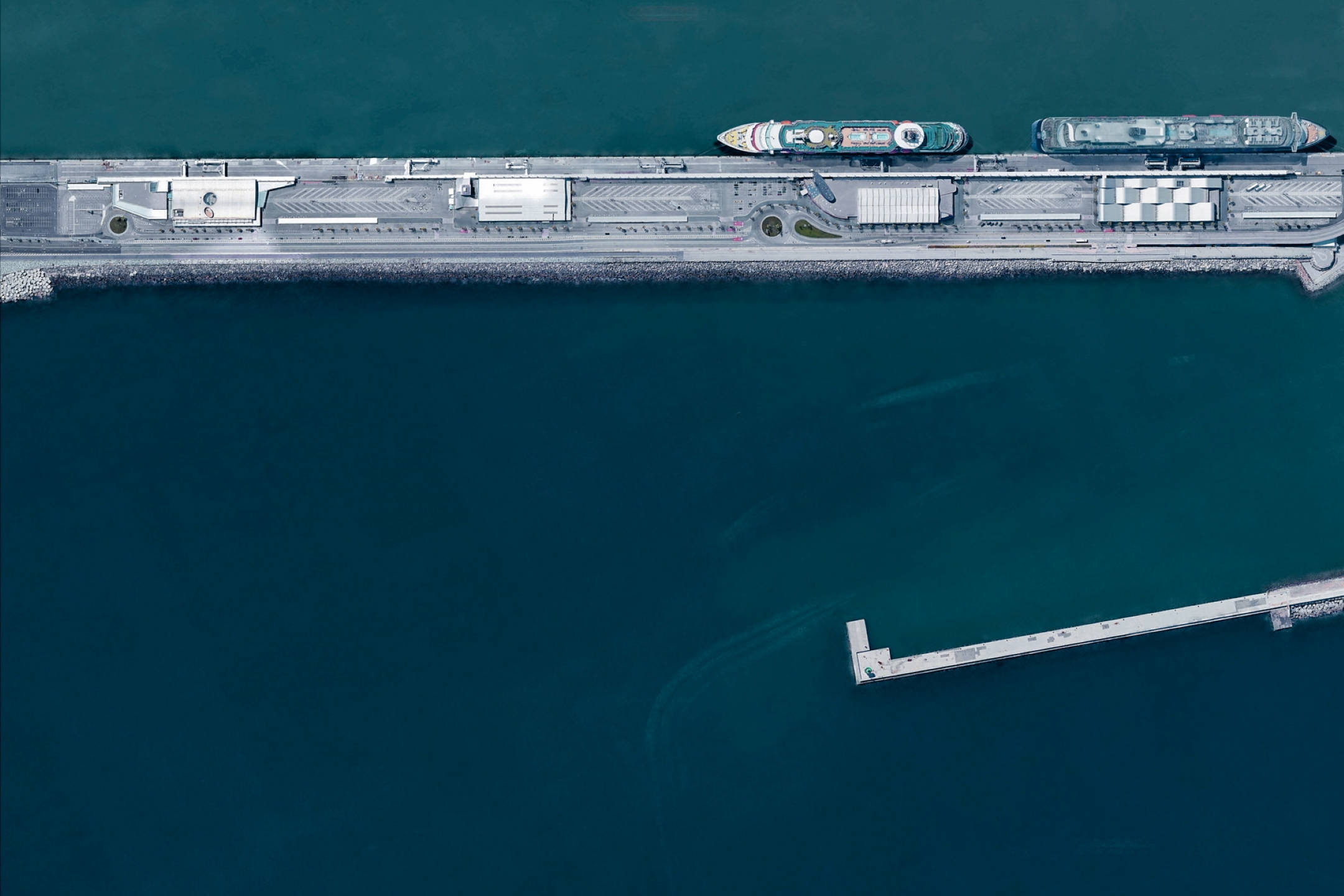 Google 地球 桌布 壁紙 — 一艘現代郵輪停泊在時尚碼頭的鳥瞰圖，周圍是深藍綠色的海水。