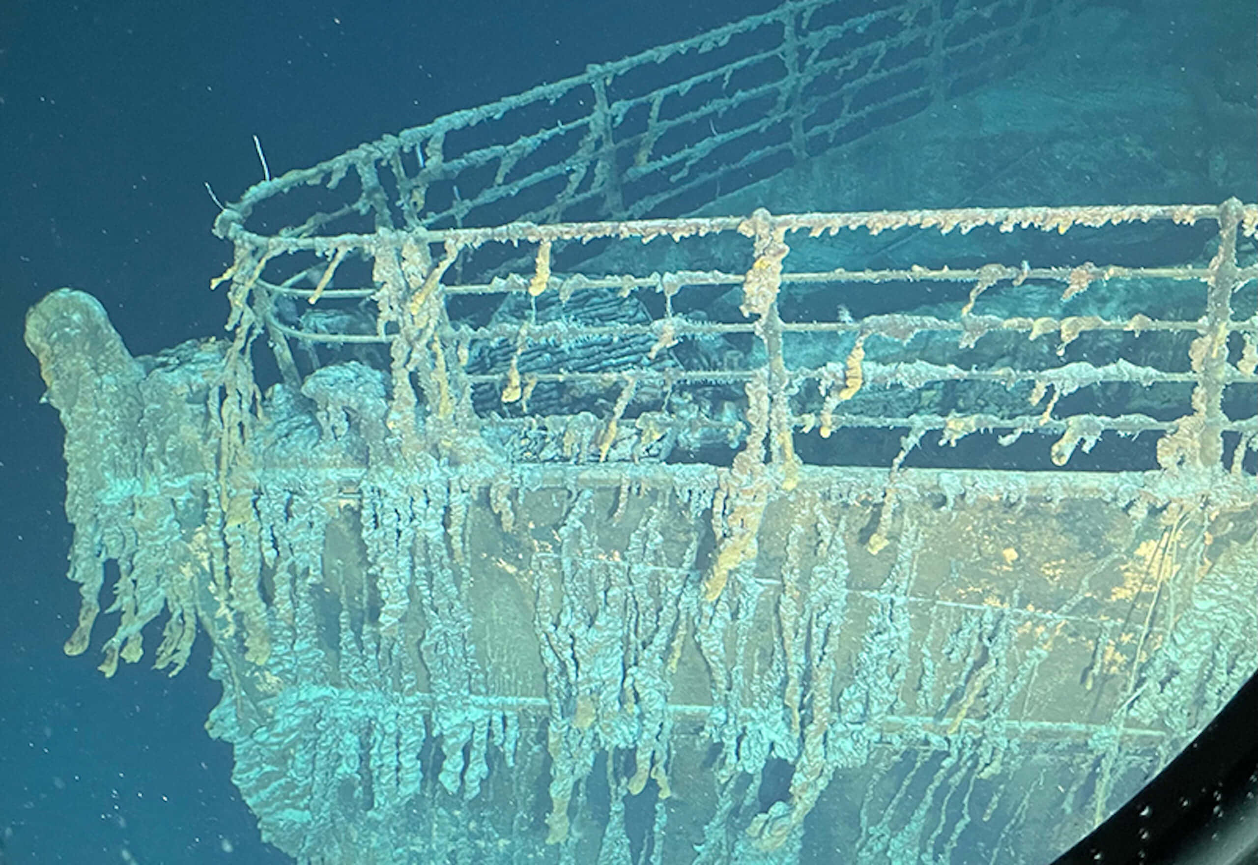 船 桌布 壁紙 — 一艘生鏽的沉船被海洋生物覆蓋，躺在深藍色海水下的海床上。