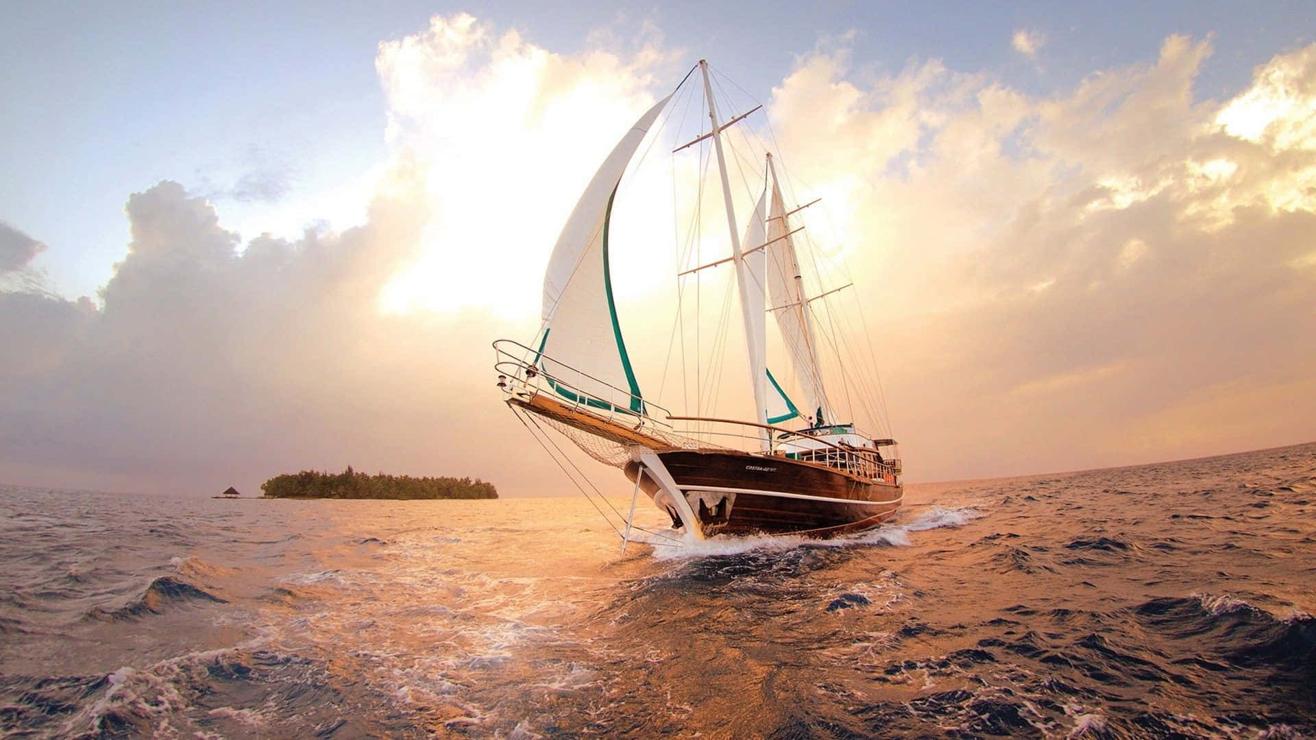 Sailboat 桌布 壁紙 — 一艘經典帆船在金色夕陽的水面上航行，遠處有一座鬱鬱蔥蔥的島嶼。