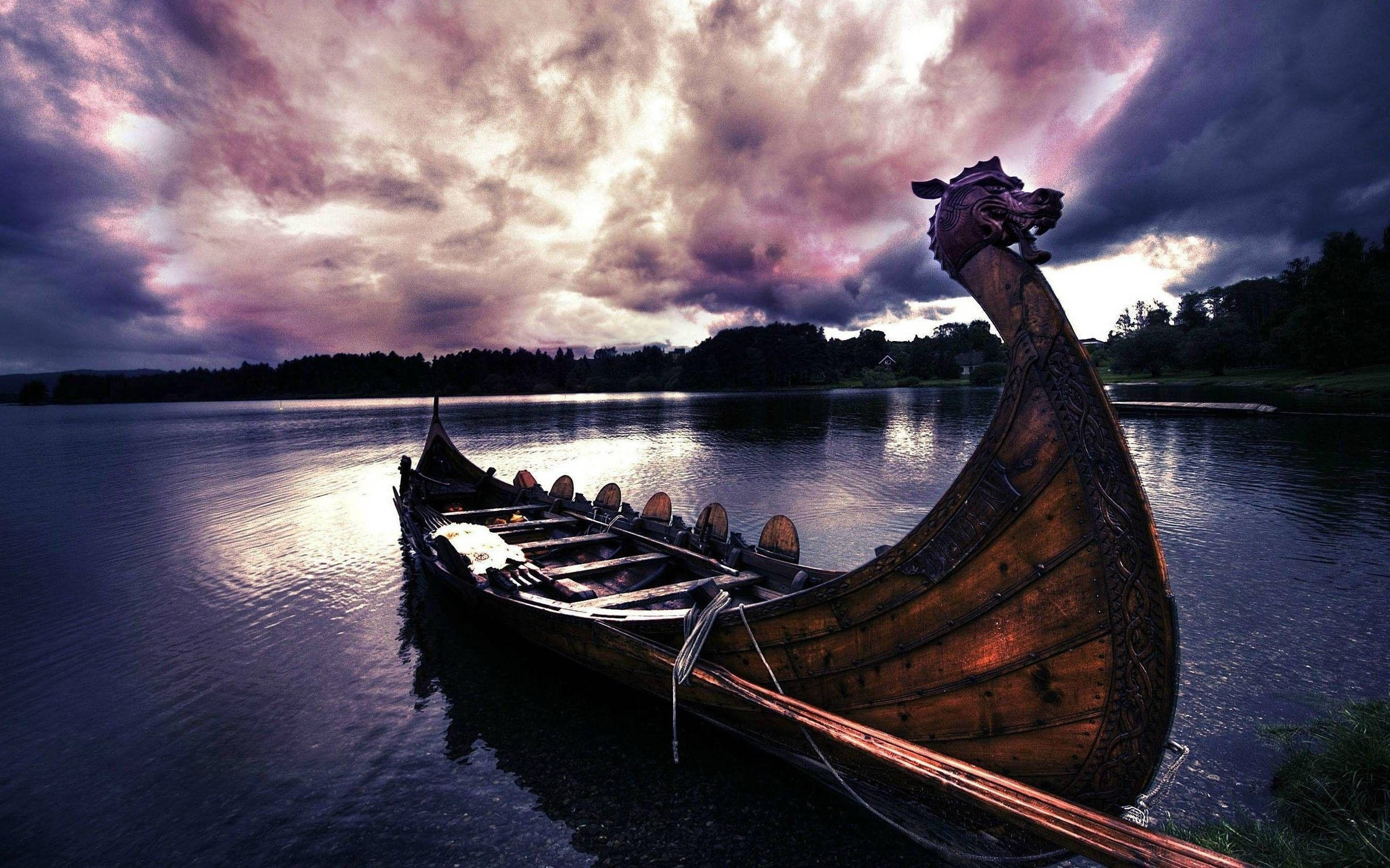 Viking Ship 桌布 壁紙 — 一艘維京長船帶有龍頭，在平靜的水面上，背景是戲劇性的紫色和灰色黃昏天空。