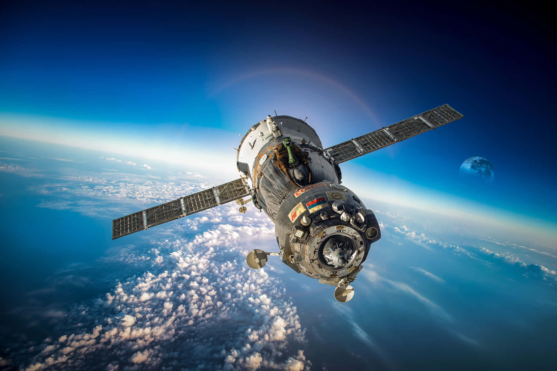 Satellite 桌布 壁紙 — 一艘詳細的太空船在地球軌道上，太陽能板展開，背景是藍色雲層和遠處的月球。