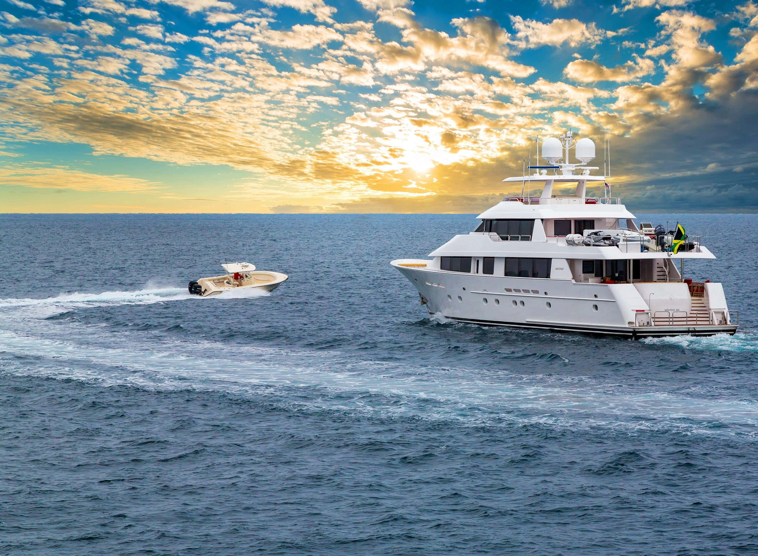 Yacht 桌布 壁紙 — 一艘豪華白色遊艇和快艇在深藍色海洋上滑行，天空是充滿活力的日落，伴隨著金色雲彩。