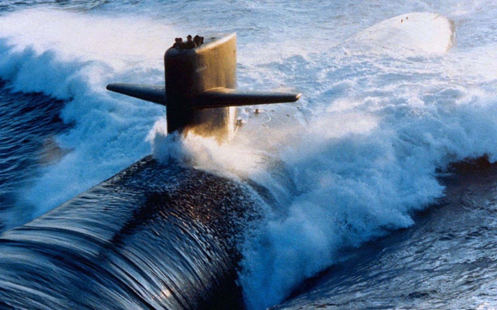 Submarine 桌布 壁紙 — 一艘軍用潛艇穿過洶湧的海浪浮出水面，激起戲劇性的白色泡沫。