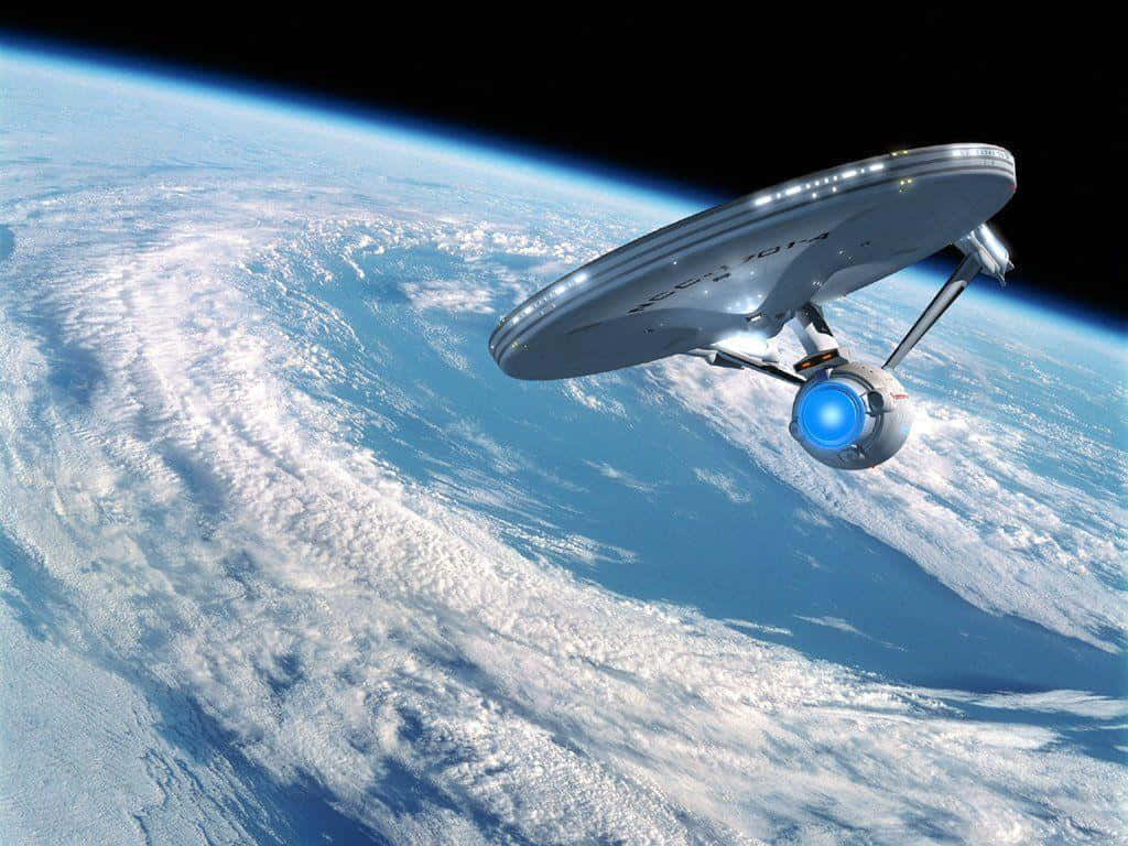 Star Trek Enterprise 桌布 壁紙 — 一艘銀色星艦在地球旋轉的藍白雲層上方滑行，背景是太空的黑色虛空。