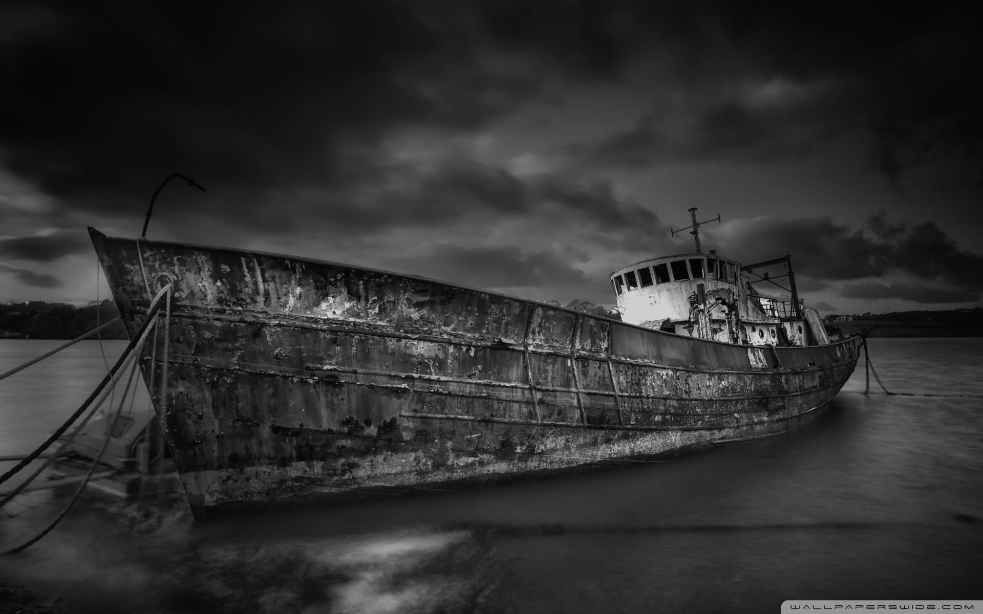 Ghost Ship 桌布 壁紙 — 一艘風化廢棄的小船在平靜的水面上紋絲不動，天空陰沉單調。
