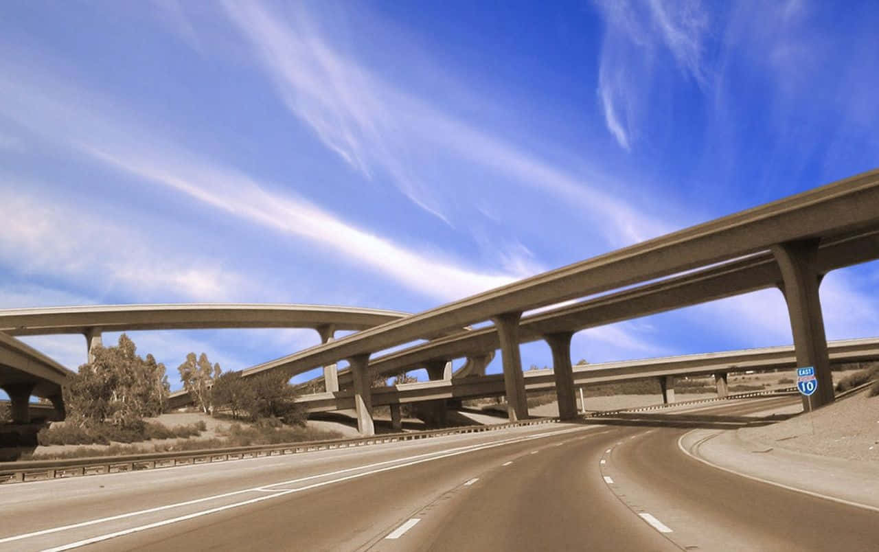 highway 桌布 壁紙 — 一覽無遺的景觀，展現分層混凝土高速公路高架橋，上方是充滿活力的藍天和縷縷白雲。