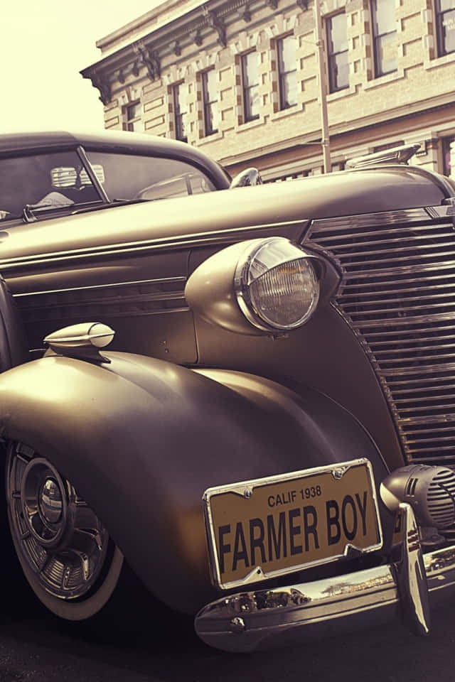 antique 桌布 壁紙 — 一輛1938年復古雪佛蘭，掛著「FARMER BOY」車牌，在溫暖陽光下於石建築旁閃閃發光。