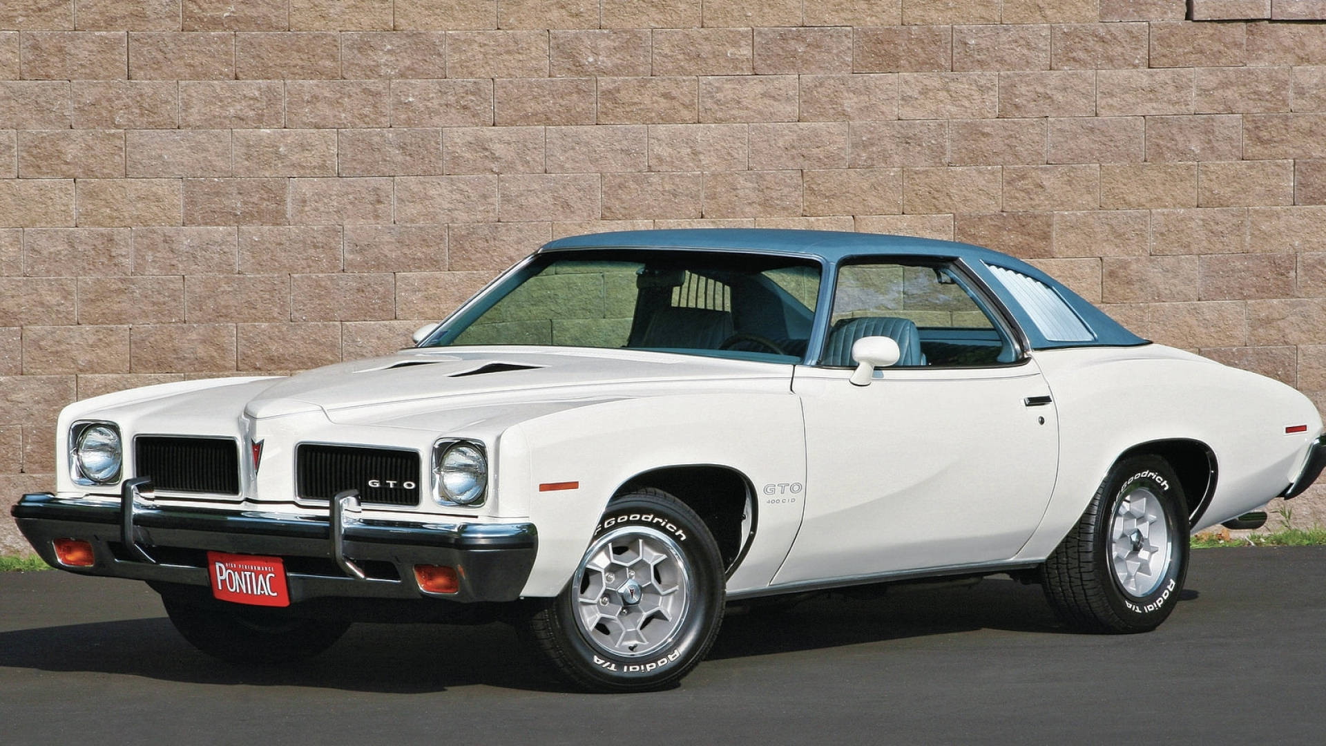 龐蒂克 桌布 壁紙 — 一輛1970年代白色Pontiac GTO肌肉車，藍色車頂，停靠在石牆旁。